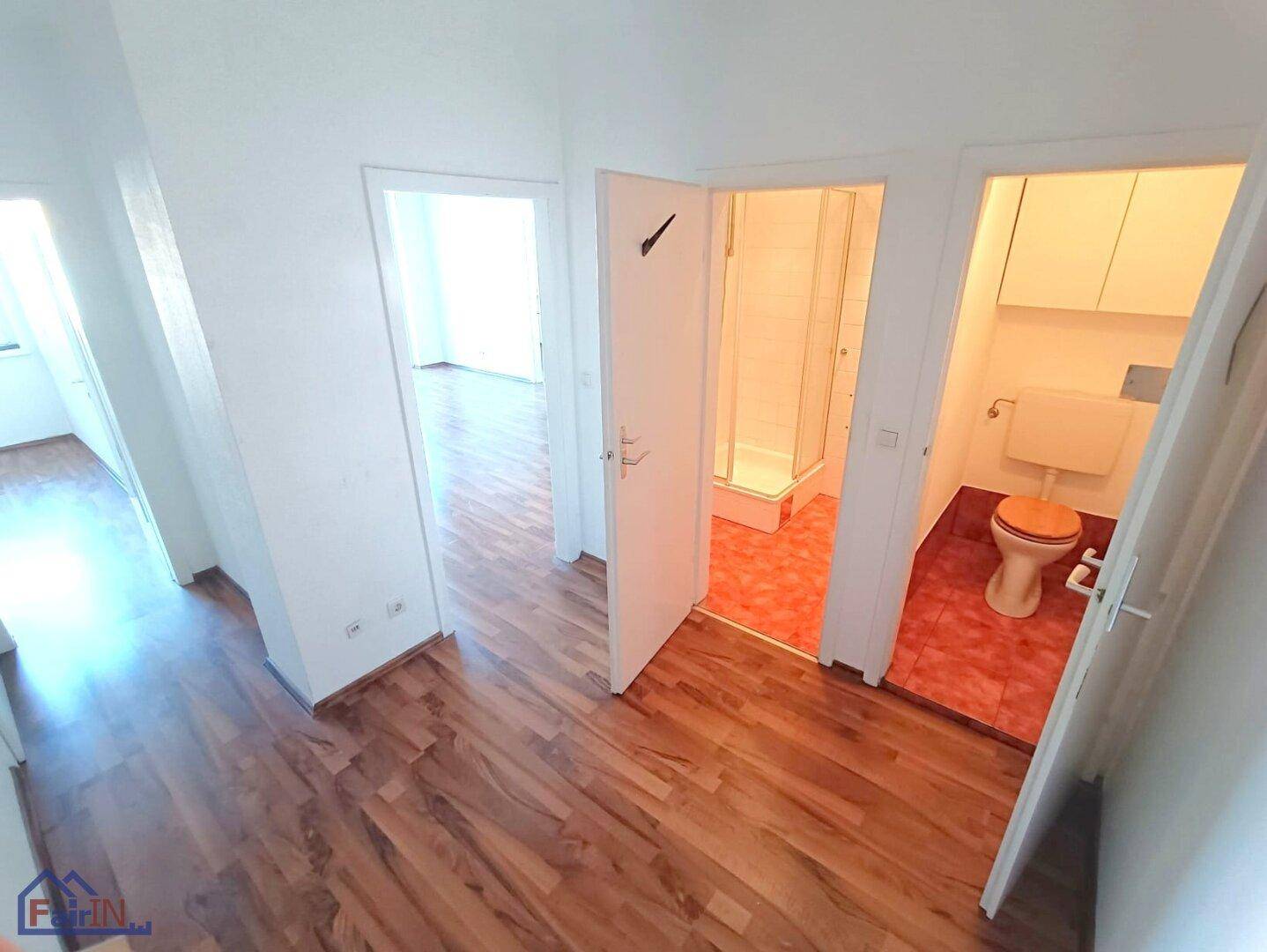 Flur mit Laminatboden und Zugängen zu Badezimmer und separatem WC.