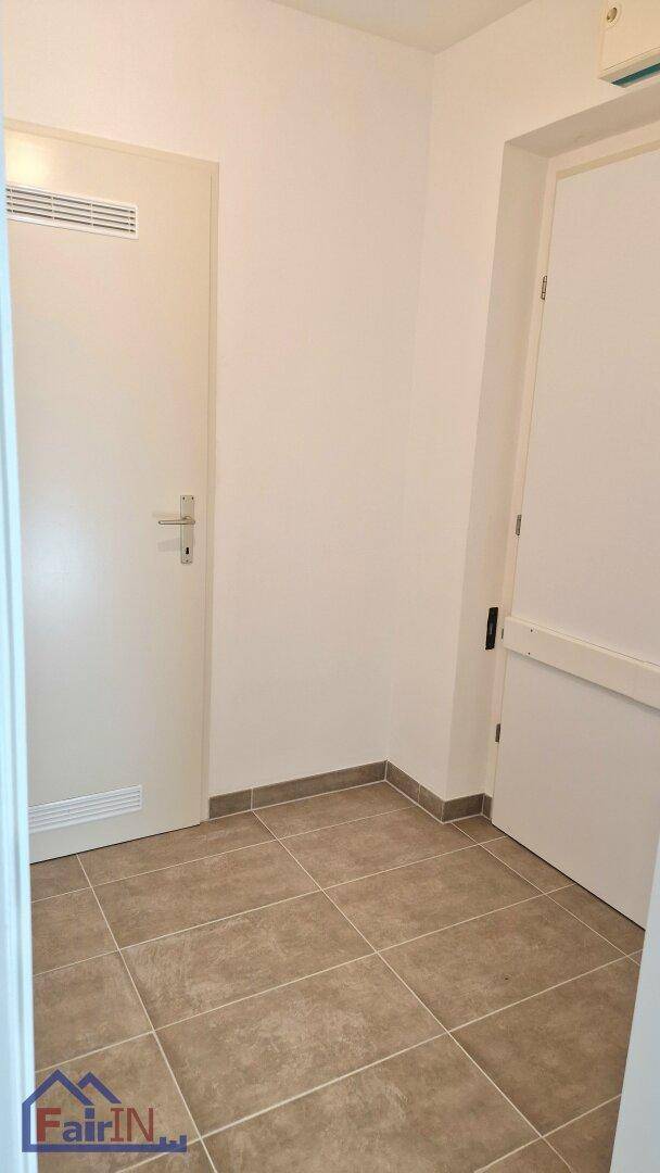 Heller Flur mit Fliesenboden und zwei Türen, die zu verschiedenen Bereichen der Wohnung führen.