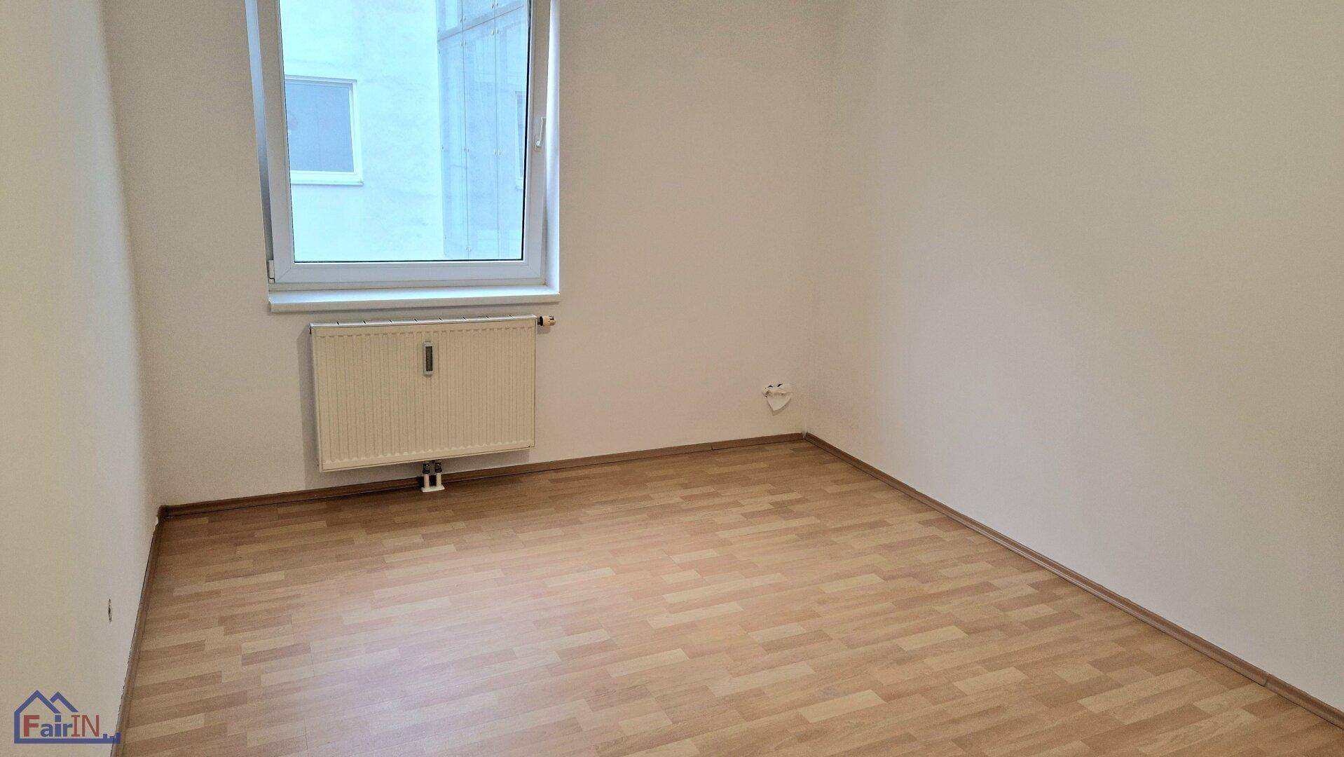 Geräumiges Schlafzimmer mit Laminatboden und einem Fenster, das für ausreichend Tageslicht sorgt.
