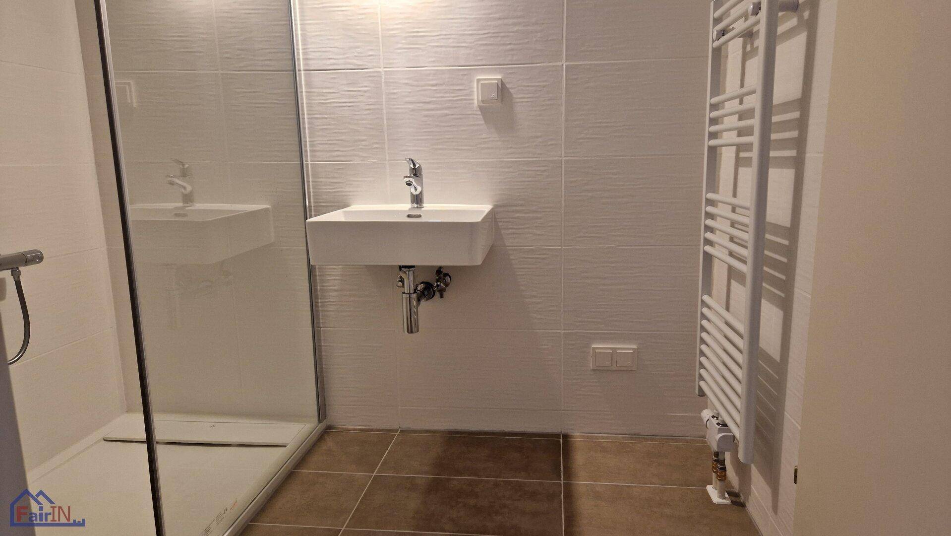 Modernes Badezimmer mit Duschbereich, Waschbecken und beheiztem Handtuchhalter.