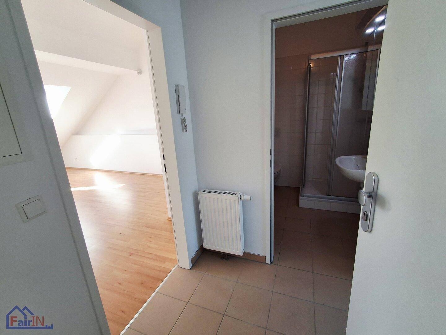 Heller Flur mit Heizkörper, der zu einem Badezimmer und einem weiteren Raum führt.