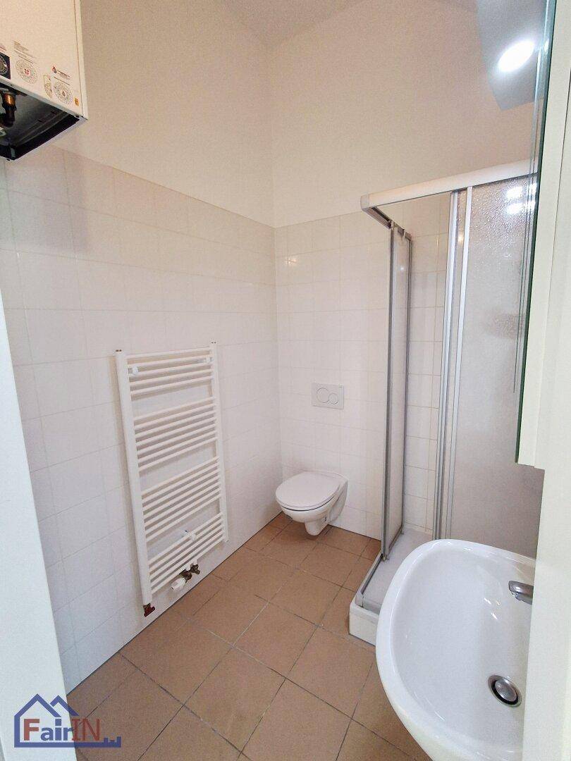 Funktionales Badezimmer mit Duschkabine, WC, Waschbecken und Handtuchheizkörper.