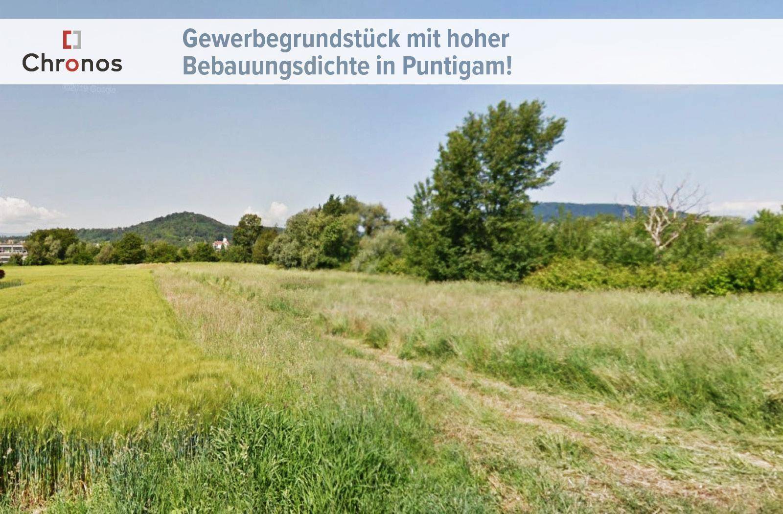 Großes Gewerbegrundstück mit weiten Feldern, Bäumen und Hügeln in der Ferne unter klarem Himmel.