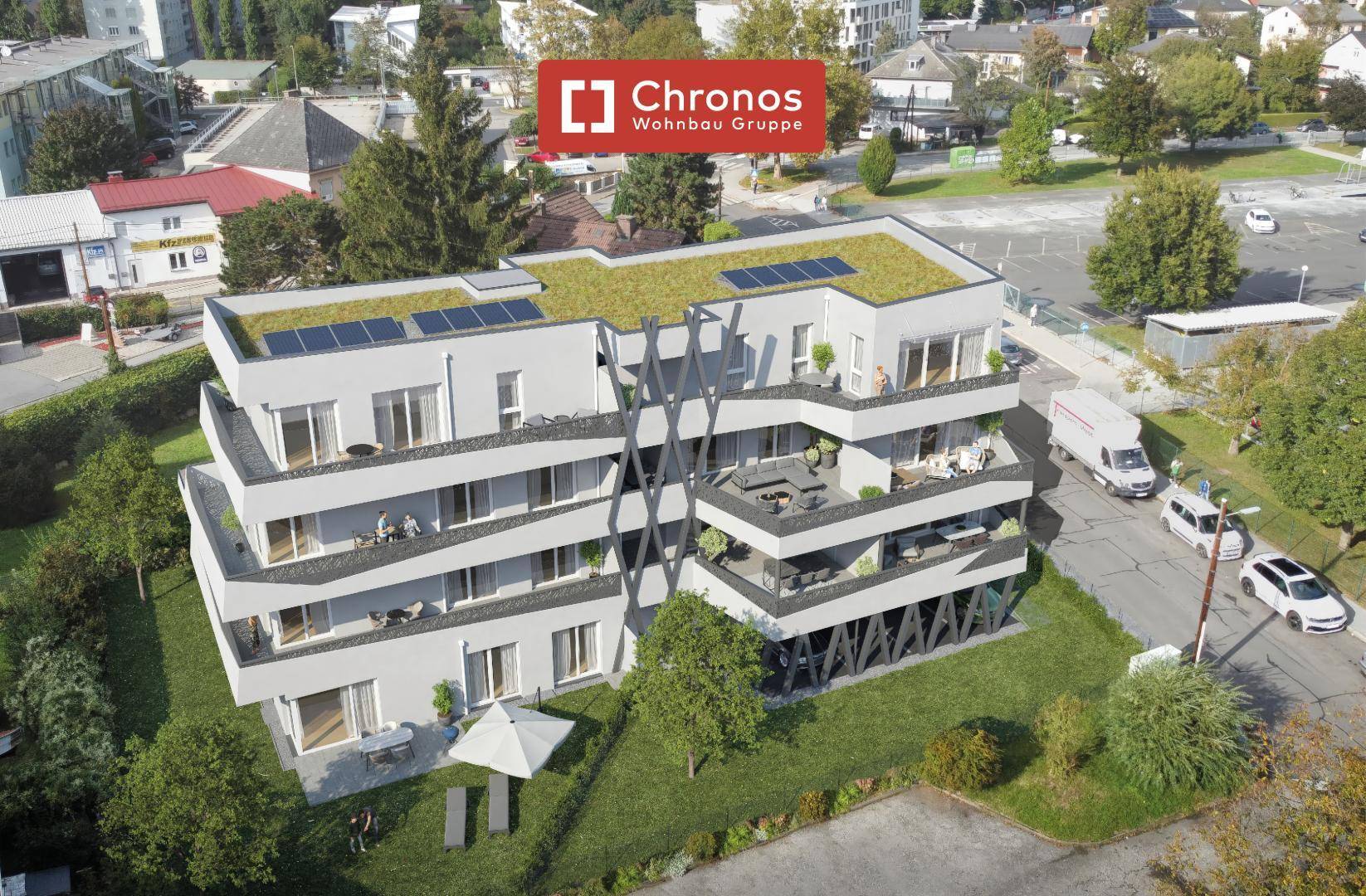 Moderne Wohnanlage mit begrüntem Flachdach, Balkonen und Solarpaneelen in grüner Umgebung.