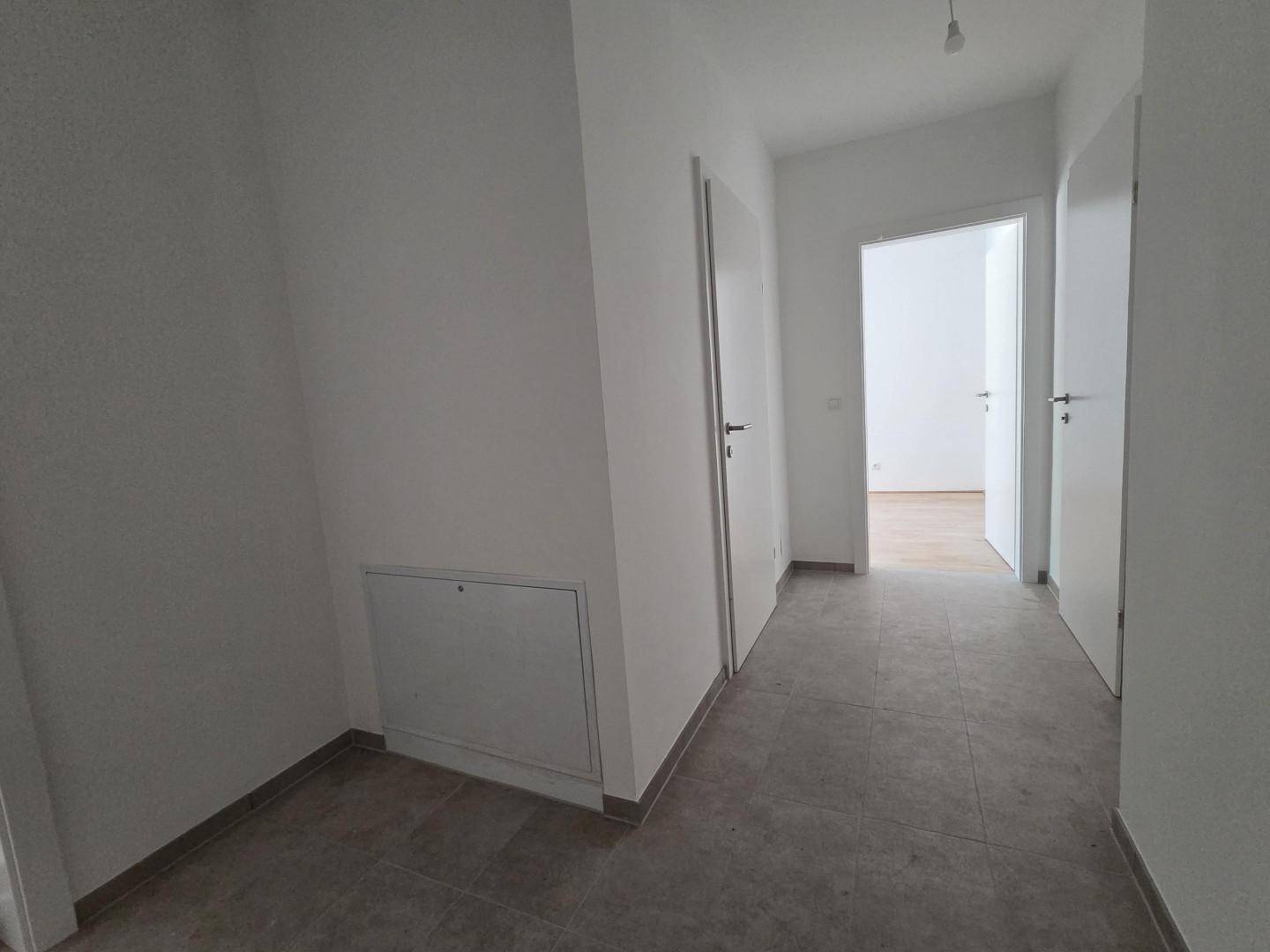 Heller Flur mit Fliesenboden und mehreren Türen, die zu den angrenzenden Räumen führen.