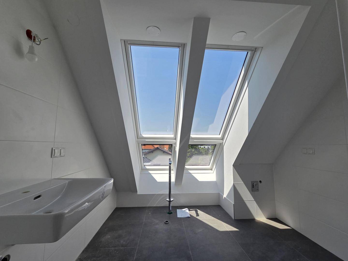 Modernes Badezimmer im Dachgeschoss mit Dachfenstern, weißen Fliesen und einem schwebenden Waschbecken.