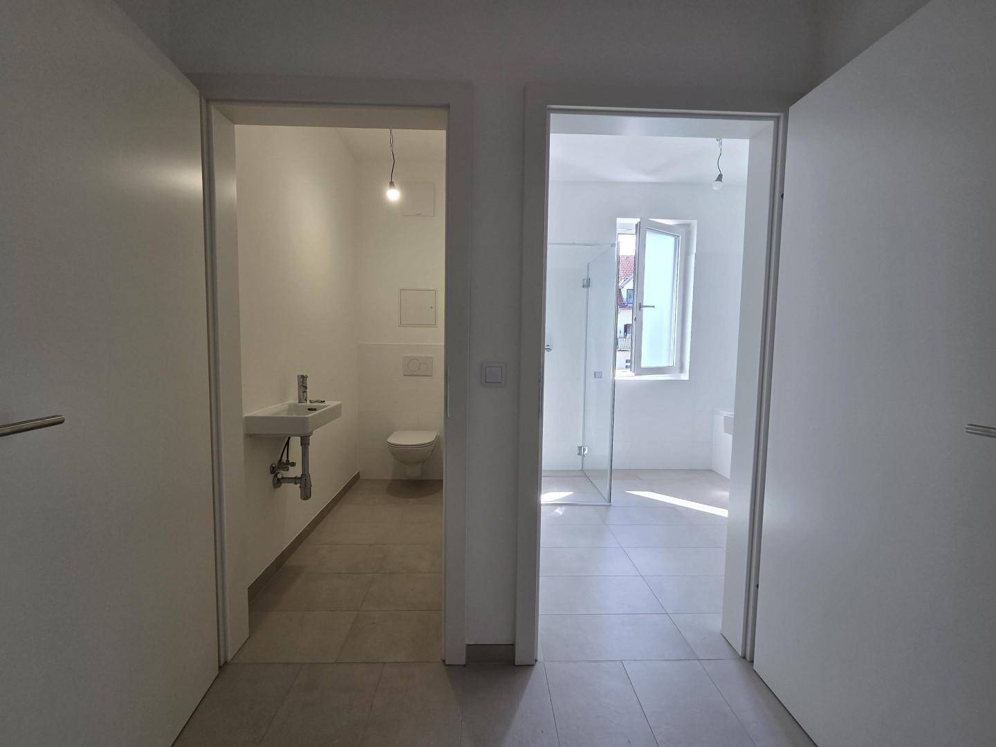 Flur mit Zugang zu einem separaten WC und einem hellen Badezimmer.