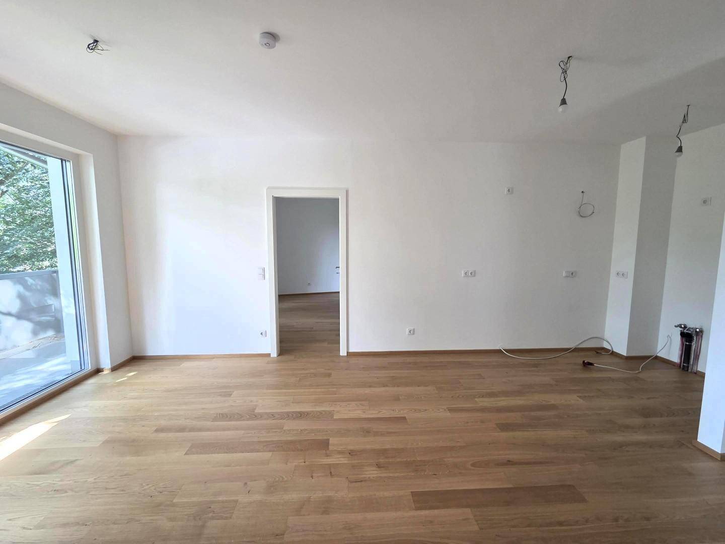 Helles Wohnzimmer mit Holzboden, weißen Wänden und viel natürlichem Licht.