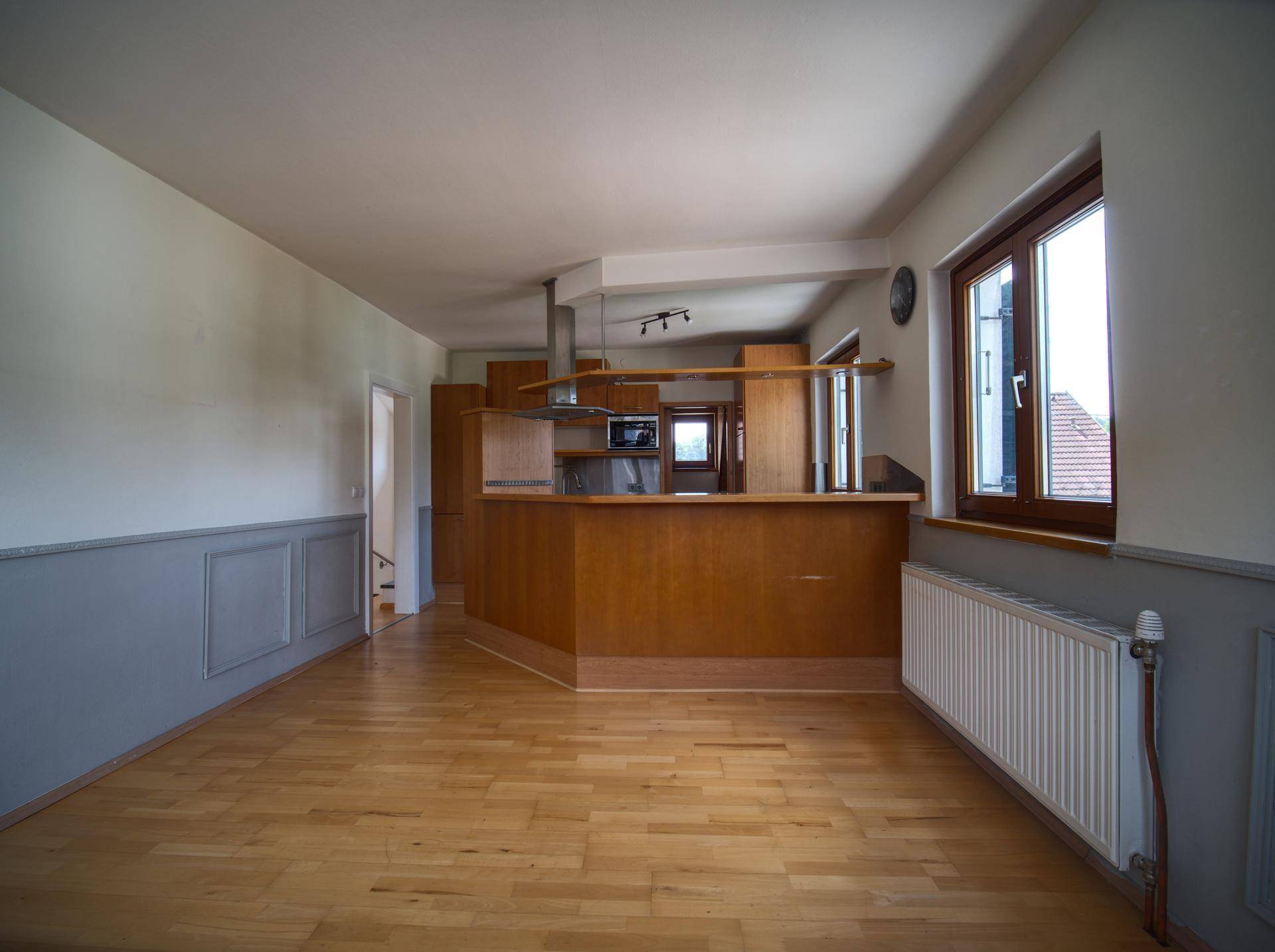 Offener Wohn-Essbereich mit Holzboden und integrierter Küche mit Frühstücksbar.