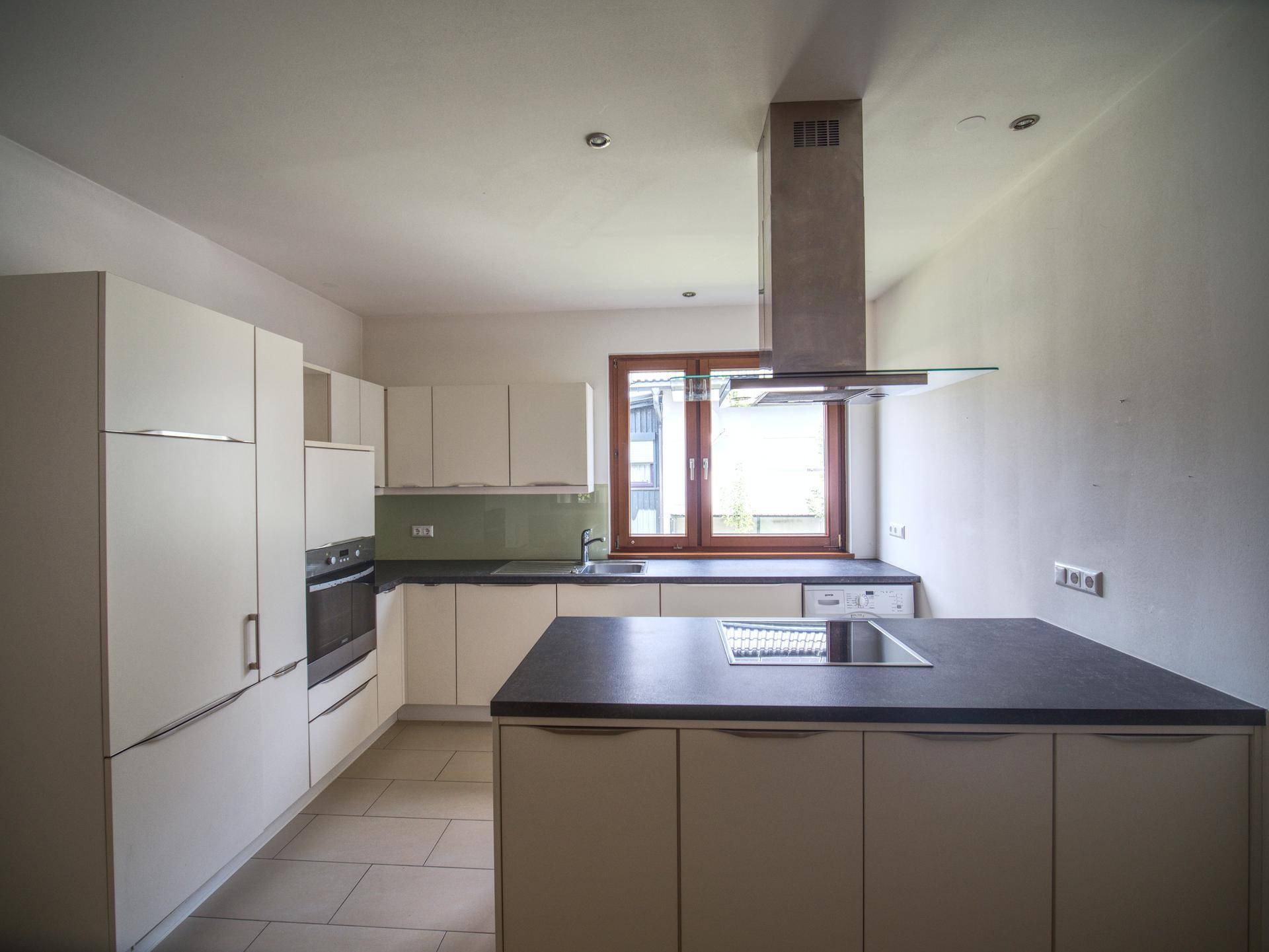 Moderne Einbauküche mit Kücheninsel, hellen Fronten und integrierten Geräten.