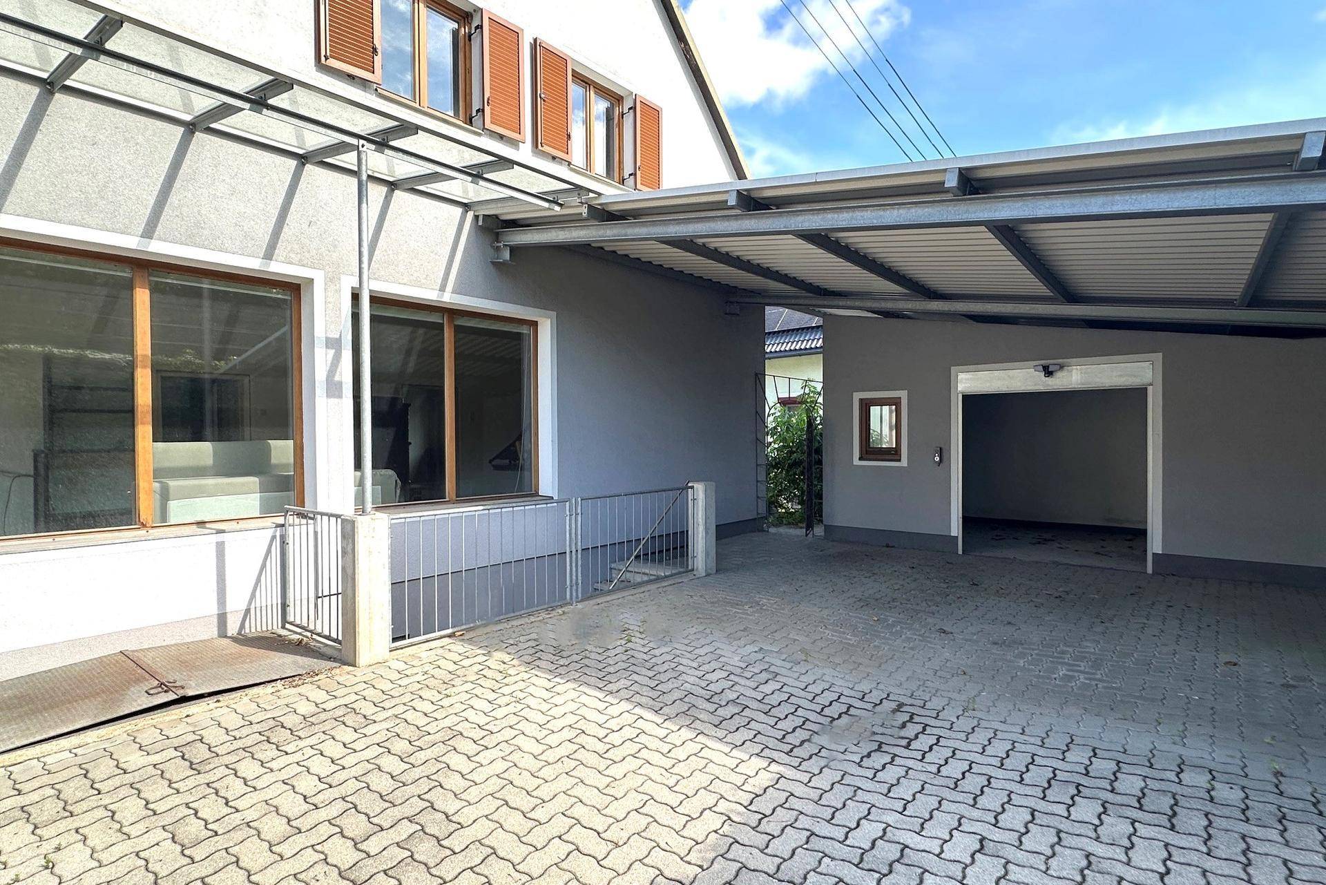 Überdachter Parkplatz und Garageneinfahrt mit Zugang zum Kellerbereich des Hauses.