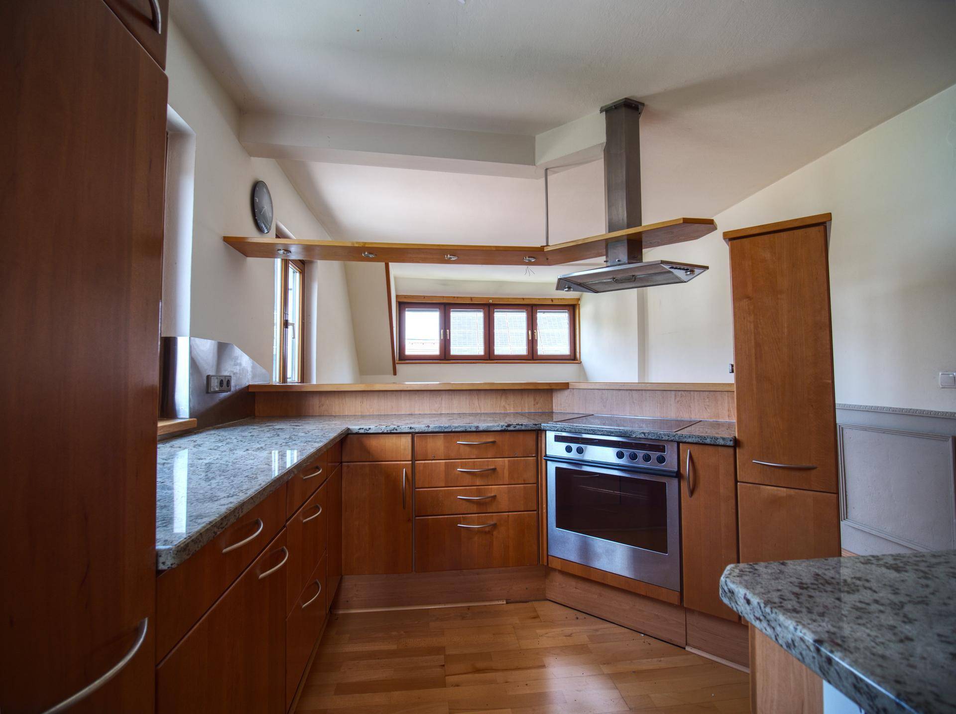 Funktionale Küche mit Holzschränken, Granitarbeitsplatten und integriertem Backofen.