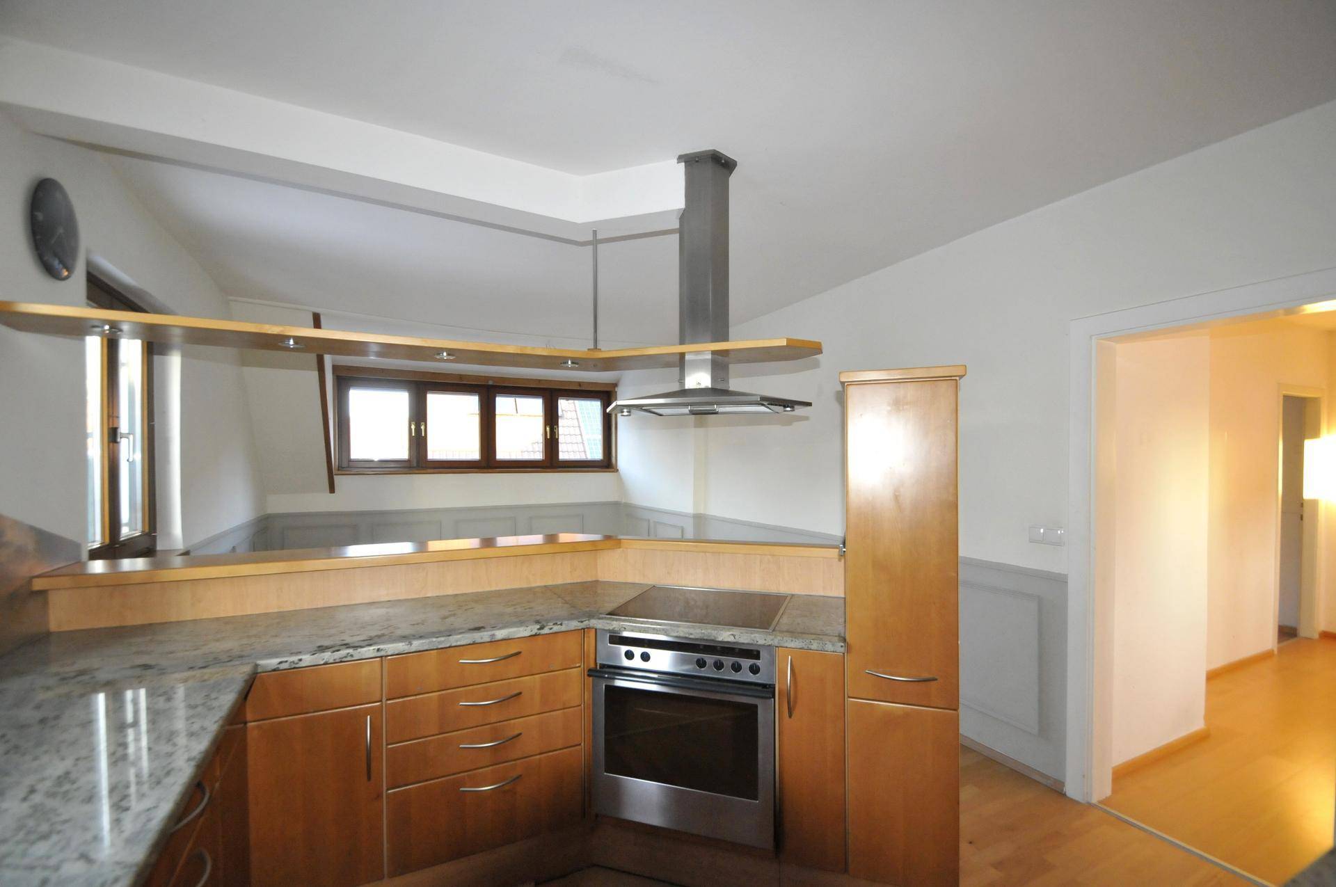 Funktionale Holzküche mit Frühstücksbar, Kochfeld und Backofen in einem halboffenen Bereich.