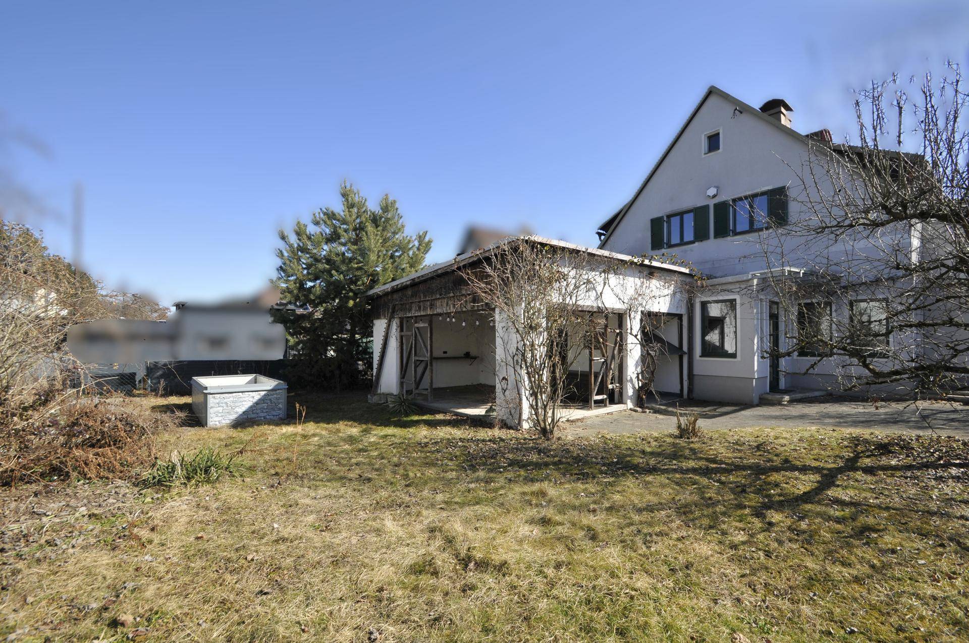 Rückansicht des Hauses mit großem Gartenbereich, Nebengebäude und sonniger Rasenfläche.