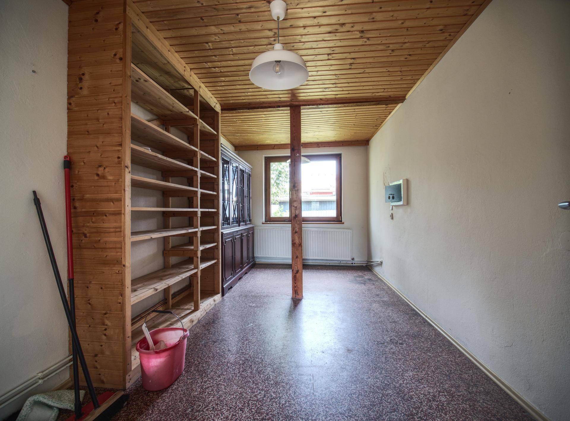 Praktischer Abstellraum mit Holzdecke, Regalen und Fenster für Tageslicht.
