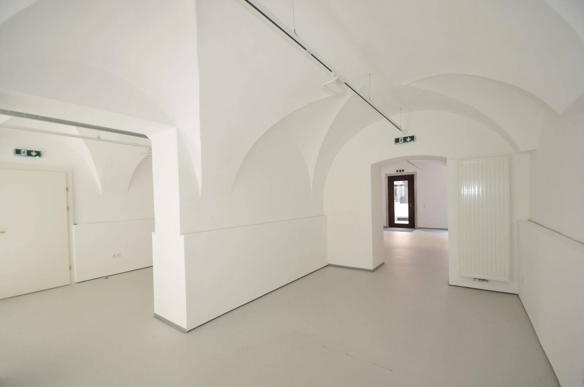 Heller Gewerberaum mit Säule, Gewölbedecken und Heizkörper an der Wand.