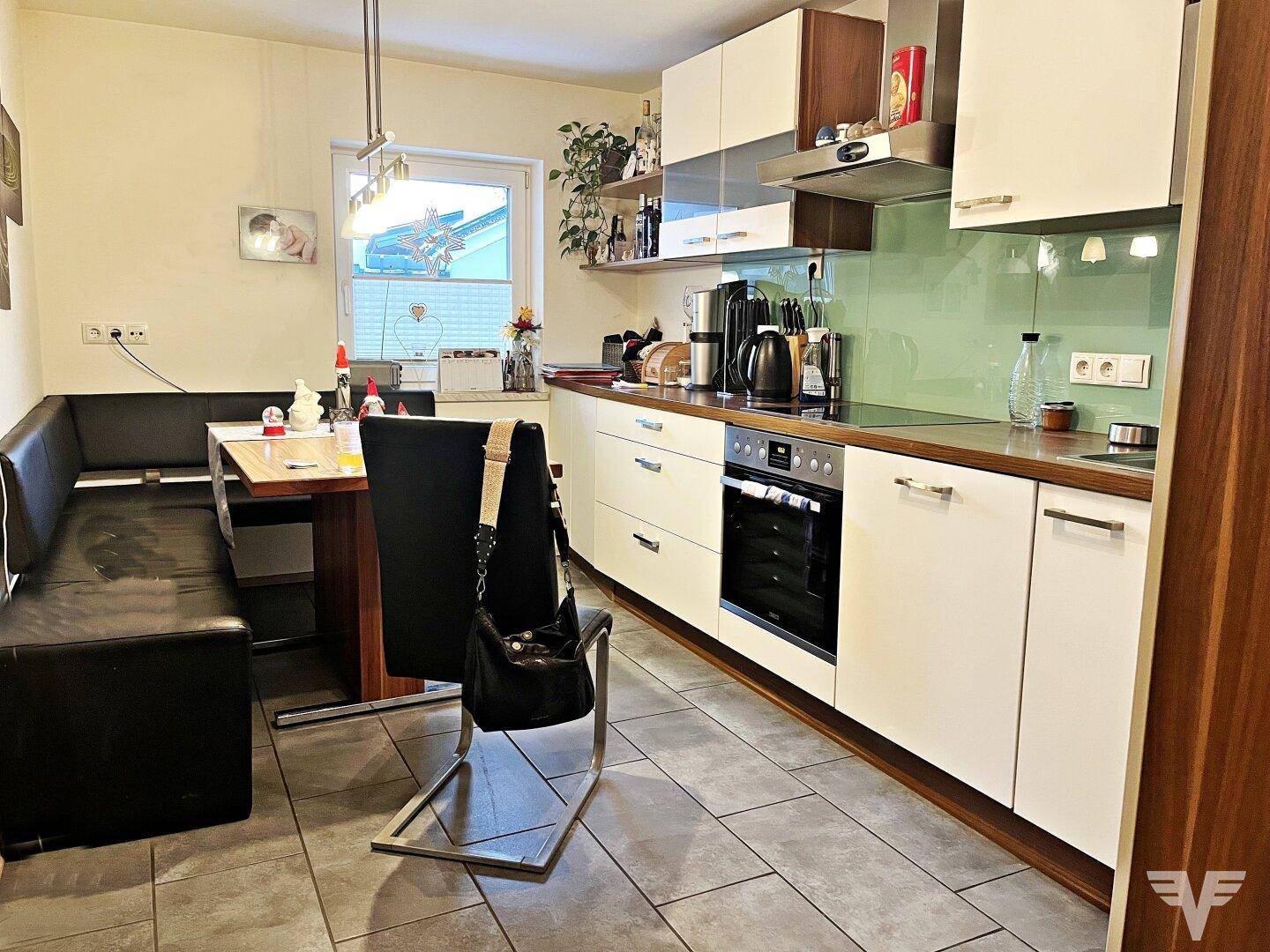 Moderne Einbauküche mit weiß-braunen Schränken, Essbereich und Fenster.