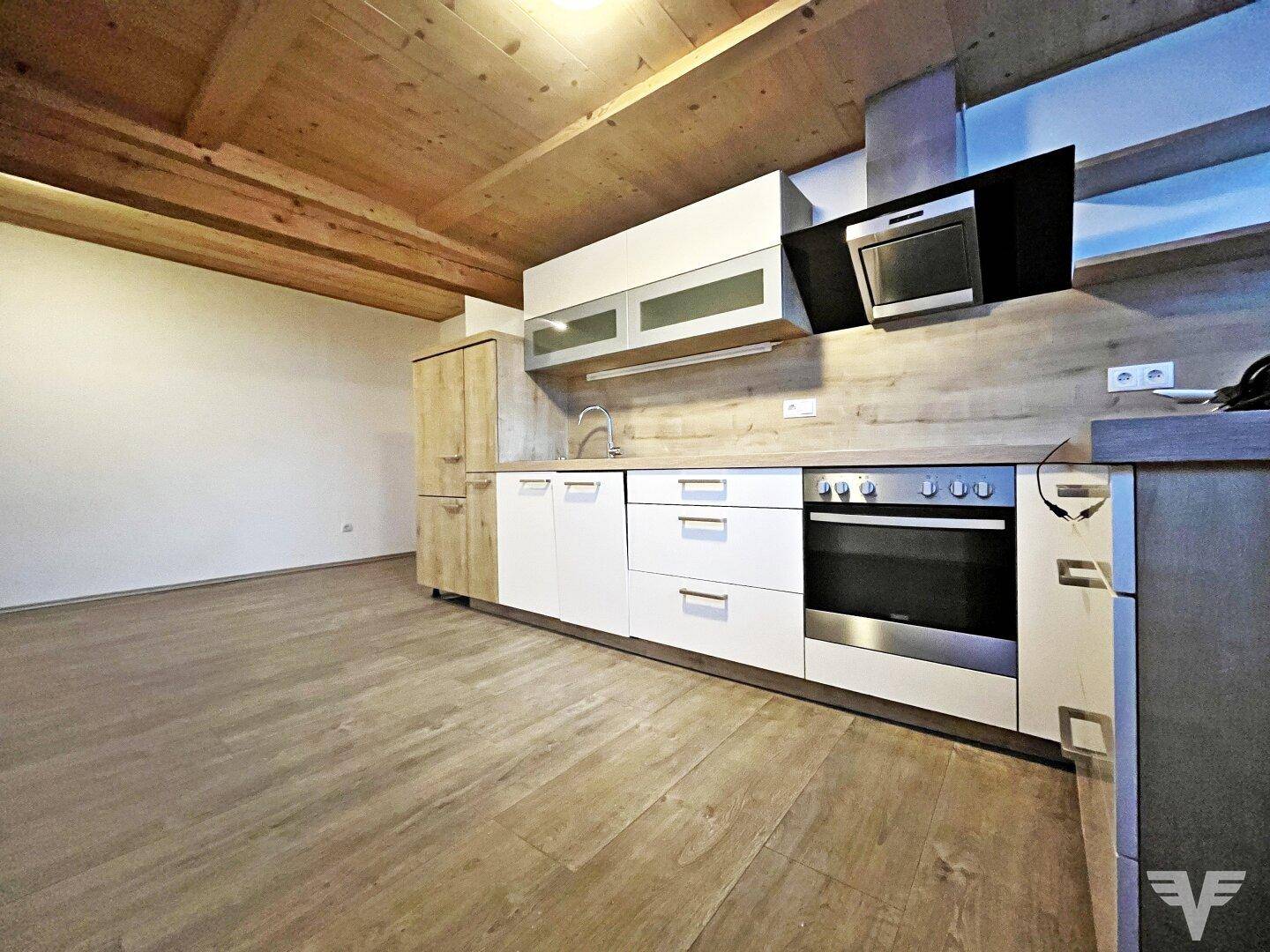 Neue Küche mit hellen Fronten, Holzarbeitsplatte und sichtbarer Holzdecke.
