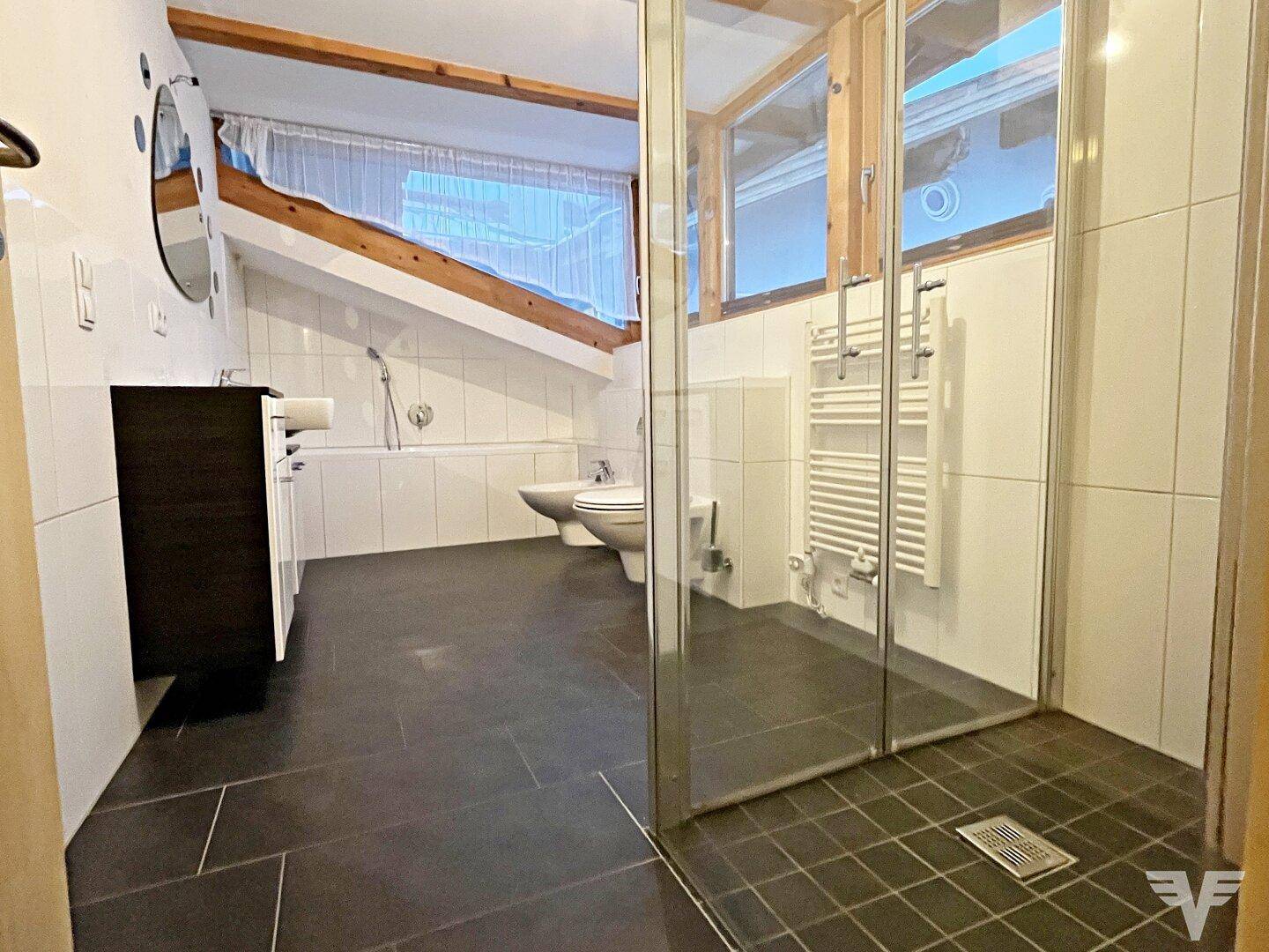 Modernes Badezimmer mit Duschkabine, Bidet und Dachschrägenfenstern.