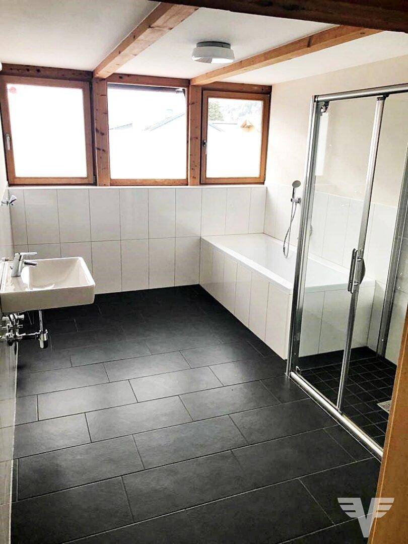 Helles Badezimmer mit Badewanne, Duschkabine und drei Fenstern.