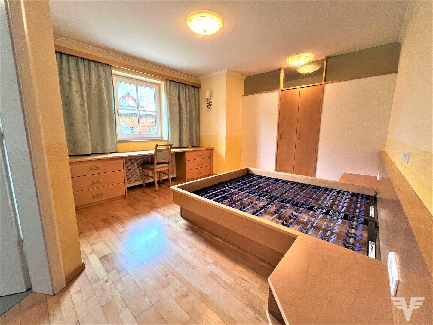 Gemütliches Schlafzimmer mit Holzbett, Schreibtisch und Einbauschränken, Parkettboden.
