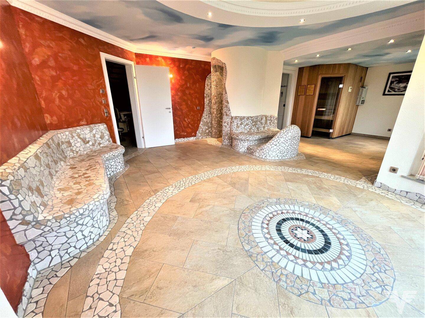Geräumiger Wellnessbereich mit Mosaikdetails und Zugang zu einer privaten Sauna.
