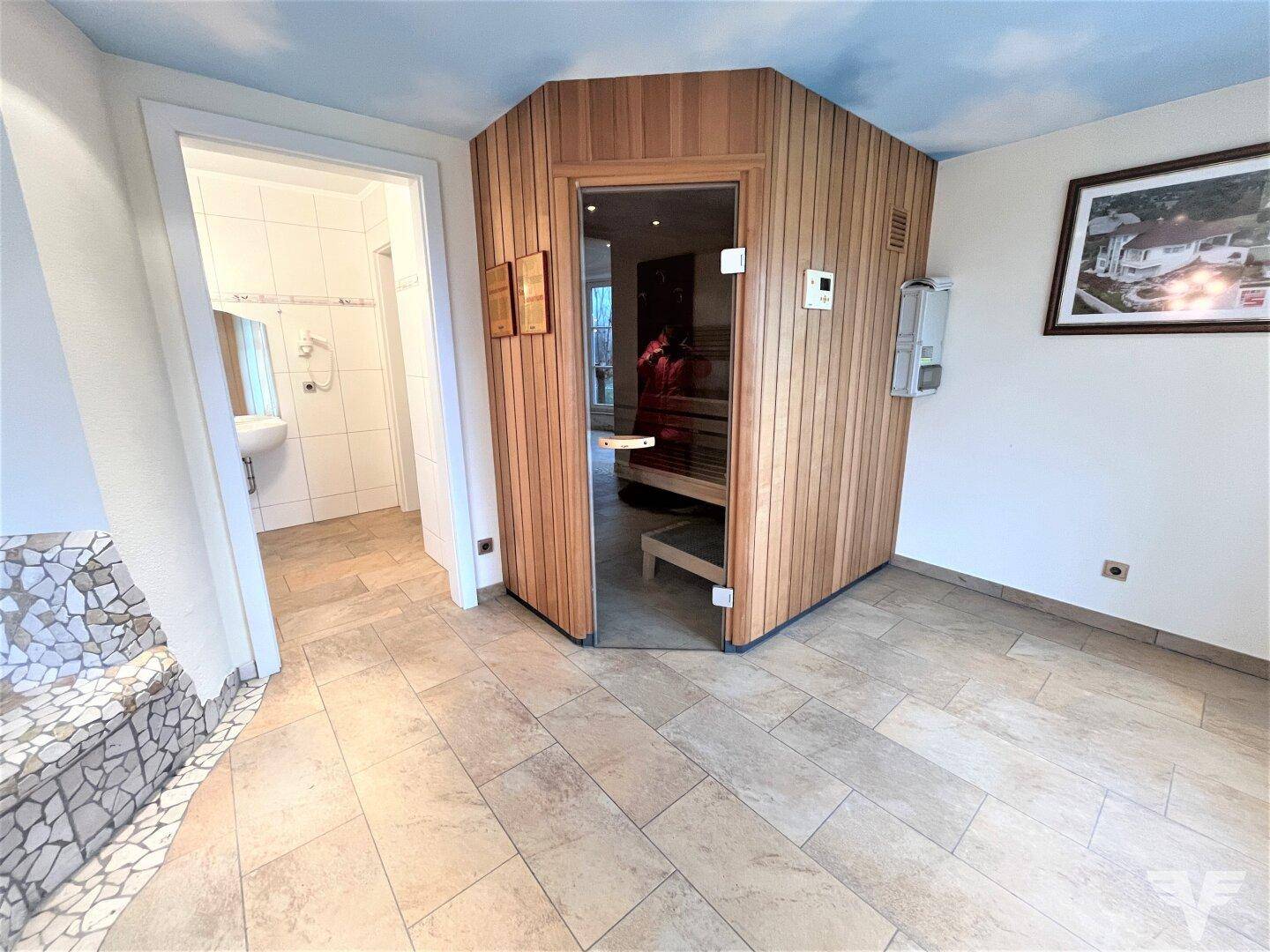 Moderne Saunakabine aus Holz im Wellnessbereich mit angrenzendem Badezimmer.