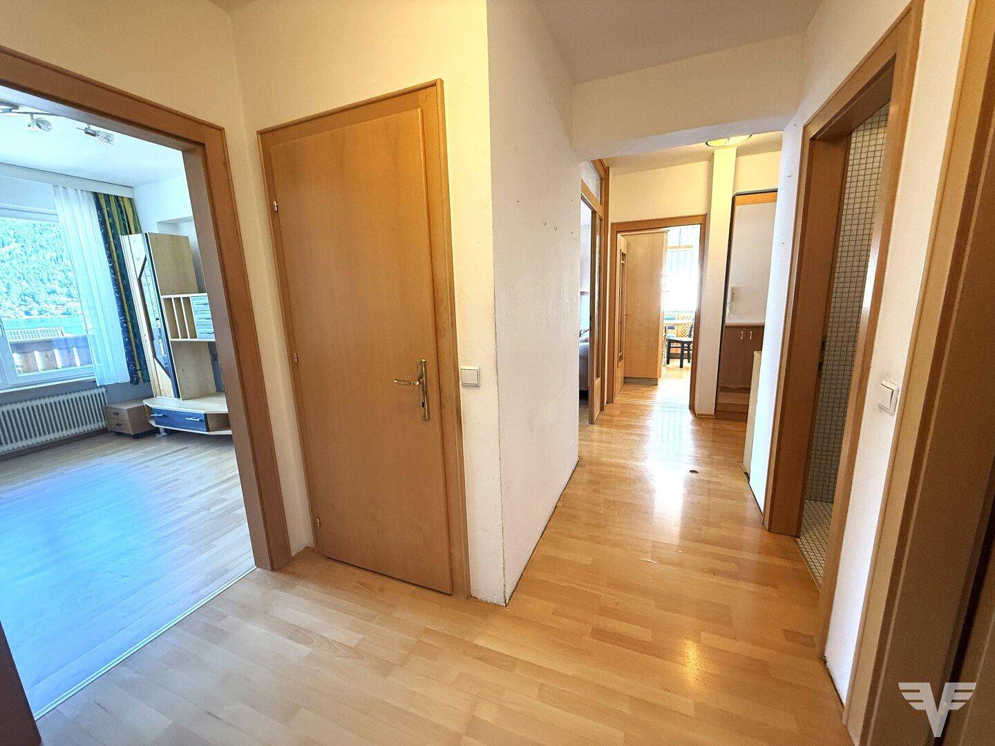 Heller Flur mit Holzboden und mehreren Türen, der zu verschiedenen Räumen führt.