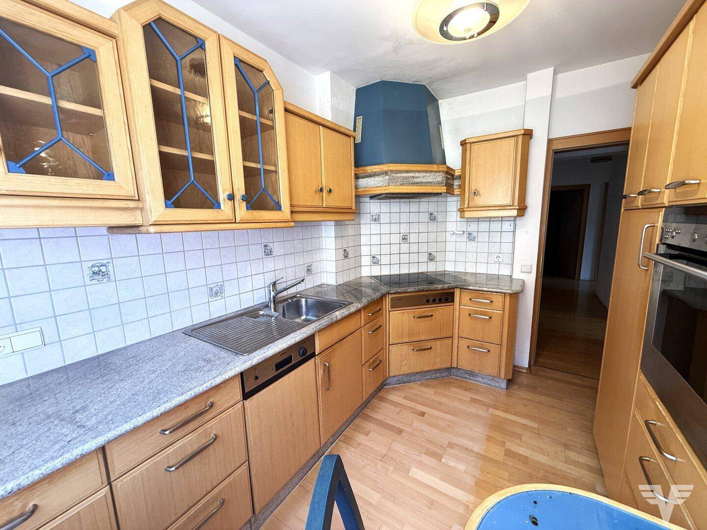 Traditionelle Einbauküche mit Holzschränken, Fliesenrückwand und integrierten Geräten.