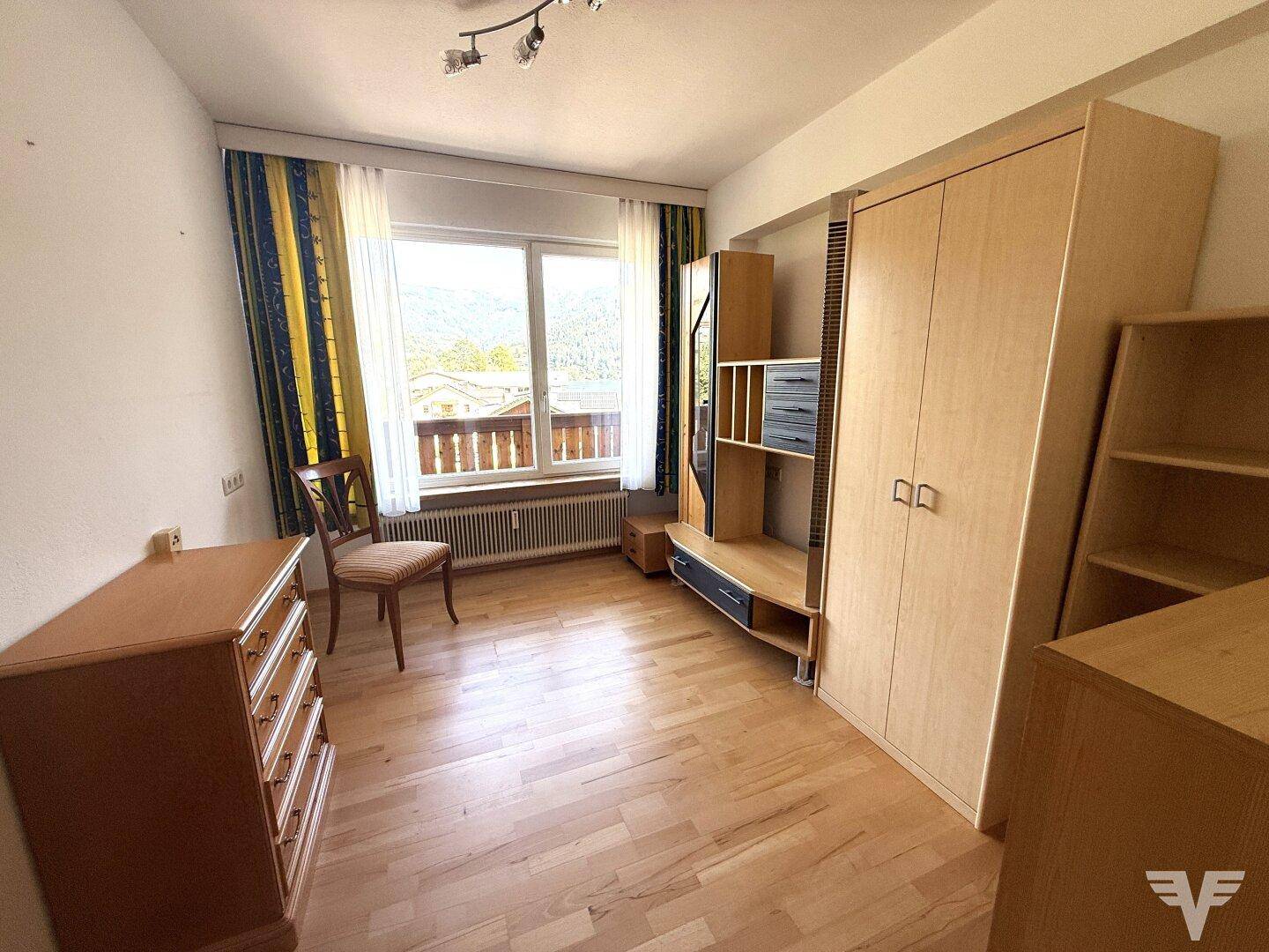 Helles Schlafzimmer mit Holzboden, großem Fenster und Einbauschränken mit Bergblick.