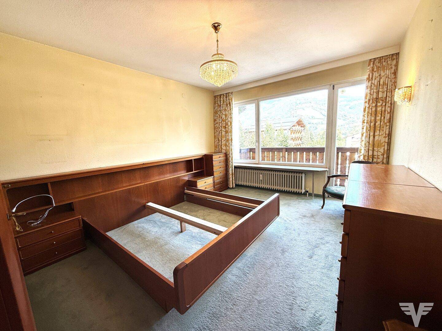 Geräumiges Schlafzimmer mit Teppichboden, großem Fenster und einem Bettrahmen aus Holz.