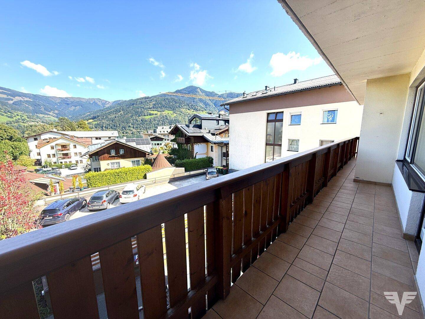 Geräumiger Balkon mit Holzgeländer und Fliesenboden, bietet einen weiten Blick auf die Umgebung.