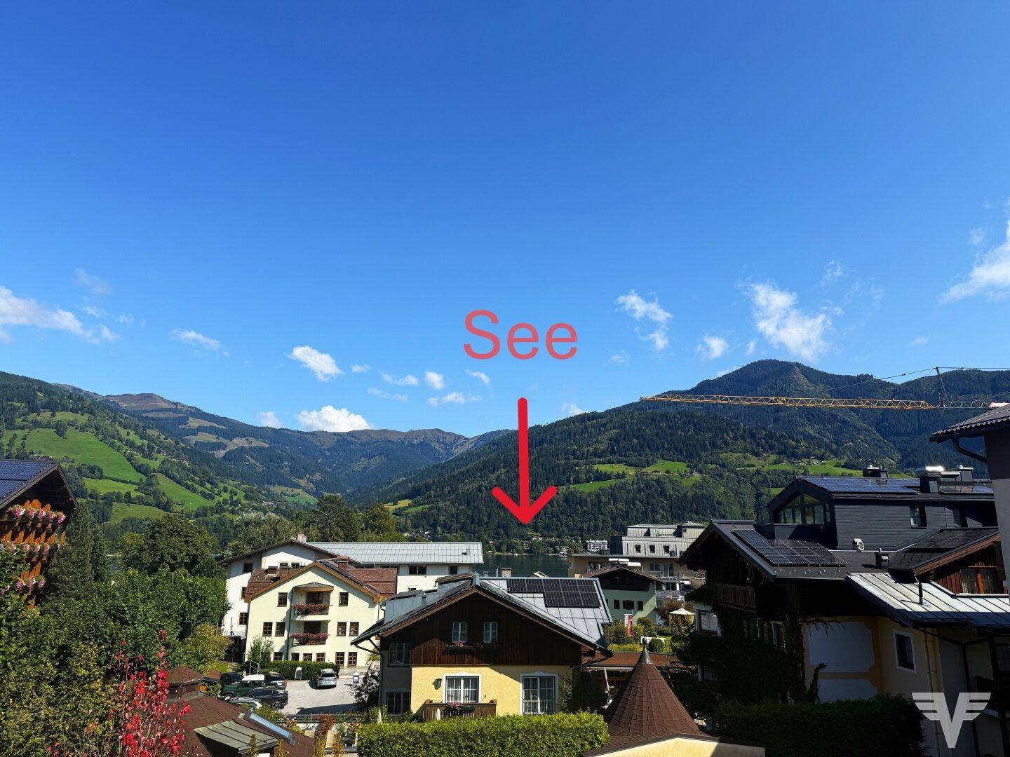 Weitblick über die Dächer der Häuser auf den See und die majestätischen Berge im Hintergrund.