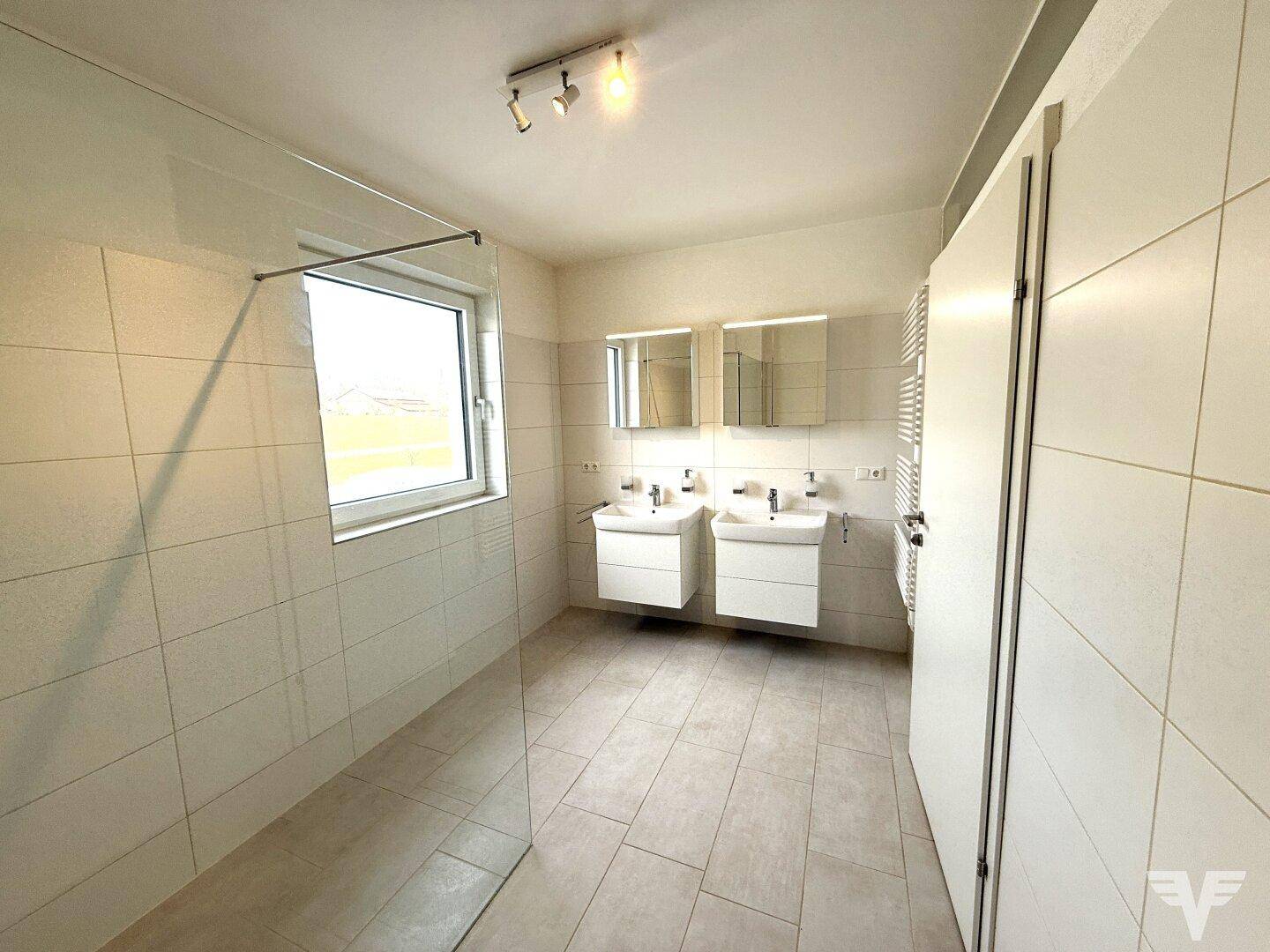 Modernes Badezimmer mit Doppelwaschbecken, großer begehbarer Dusche und Fenster.