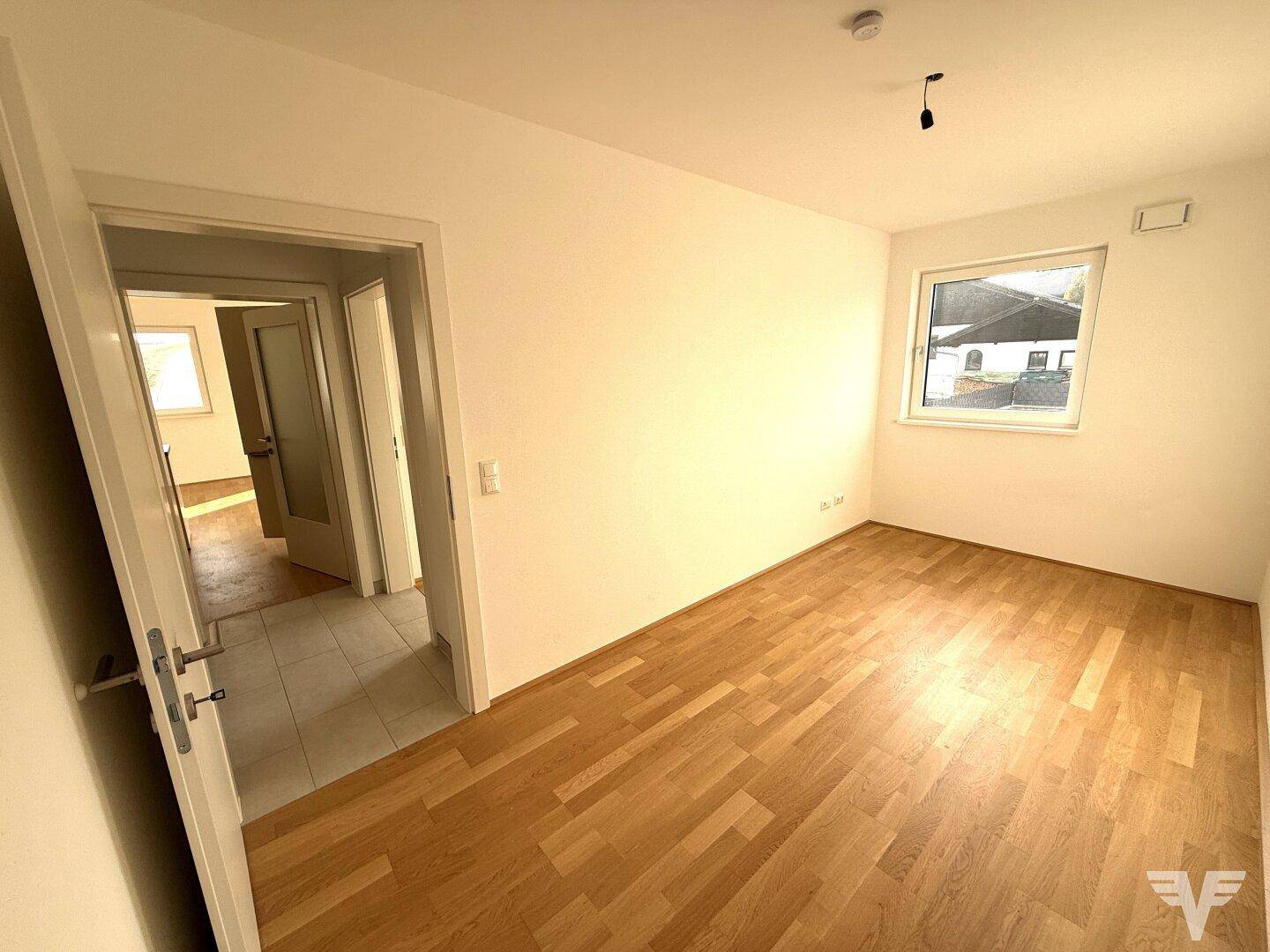 Geräumiges Zimmer mit Holzboden und Zugang zum Flur, ideal als Schlaf- oder Kinderzimmer.