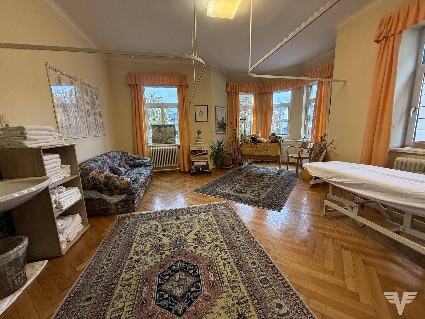 Geräumiger Raum mit Fischgrätparkett, großen Fenstern und traditionellen Teppichen, ideal für Wohnen oder Arbeiten.