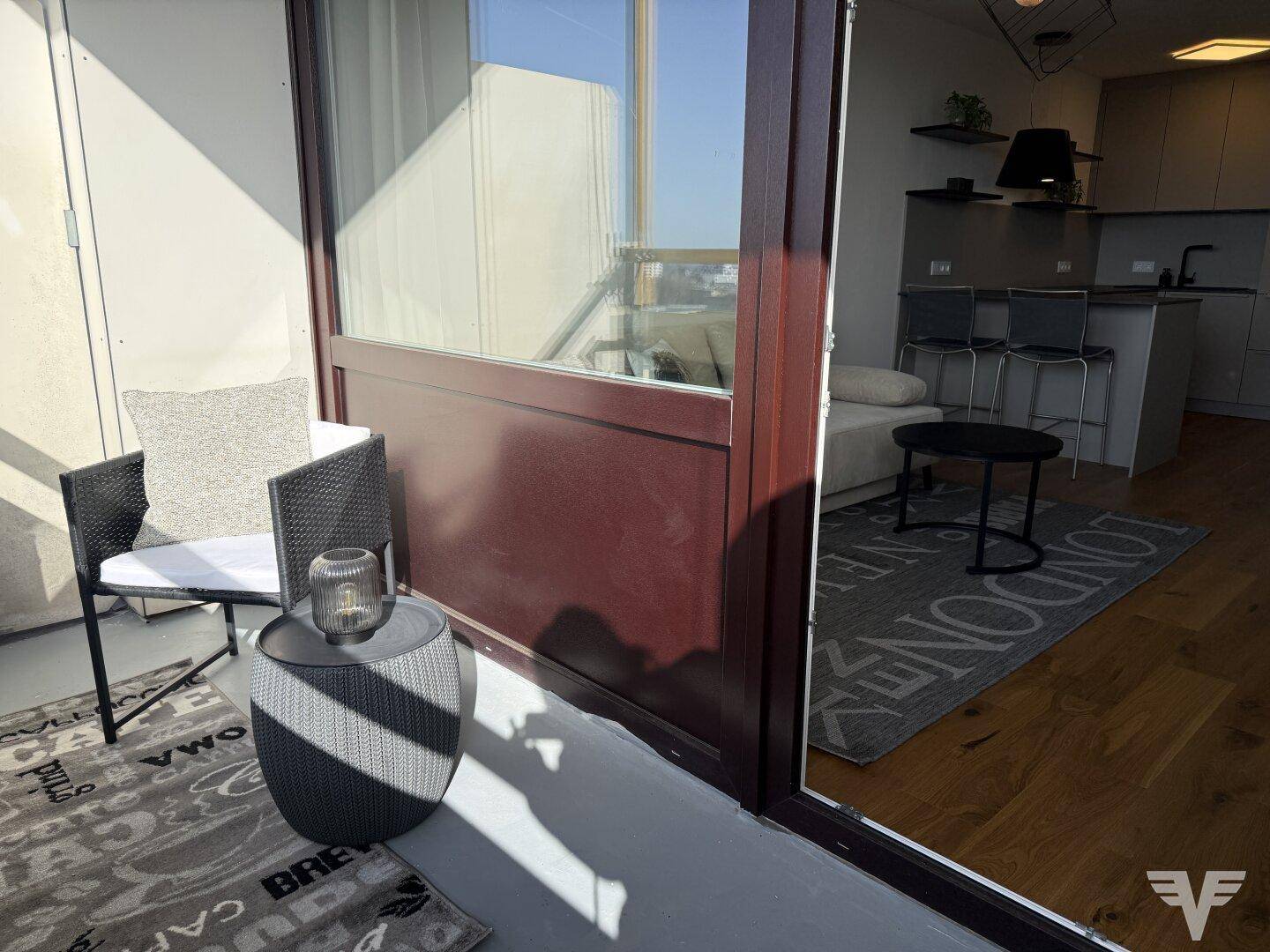 Gemütlicher Balkon mit Sitzgelegenheiten und Blick in den hellen Wohnbereich.
