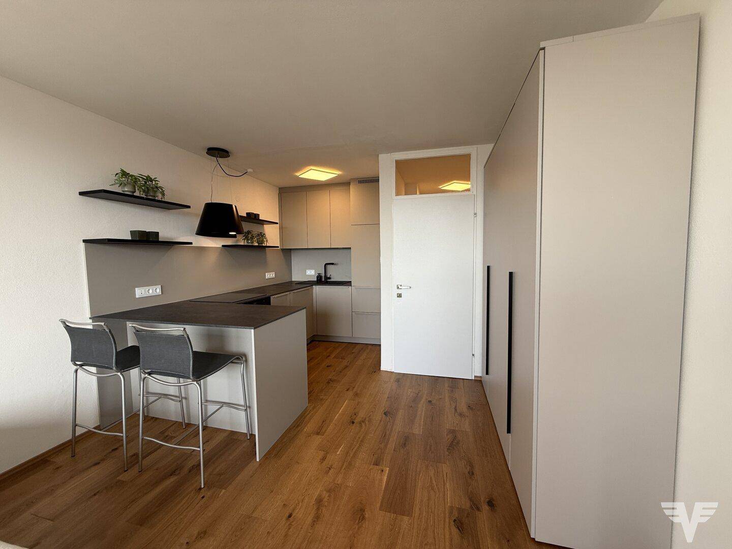 Moderne Küche mit integrierter Kücheninsel, Barhockern und Holzfußboden in hellem Ambiente.