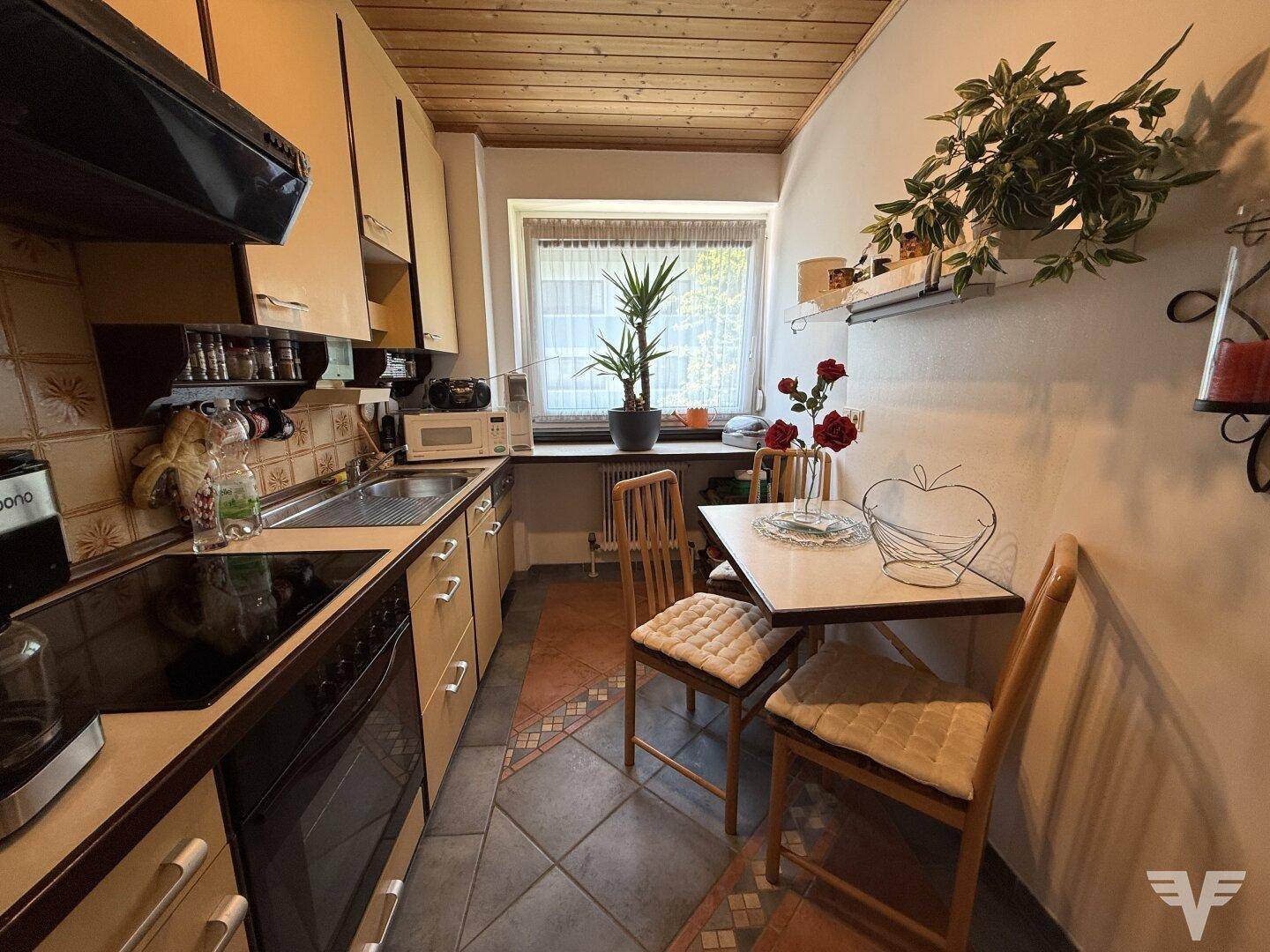 Kleine, gemütliche Küche mit Essbereich, Holzdecke und Blick ins Grüne.