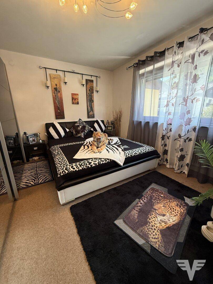 Schlafzimmer mit Doppelbett, auffälliger Tierfell-Dekoration und großem Fenster.