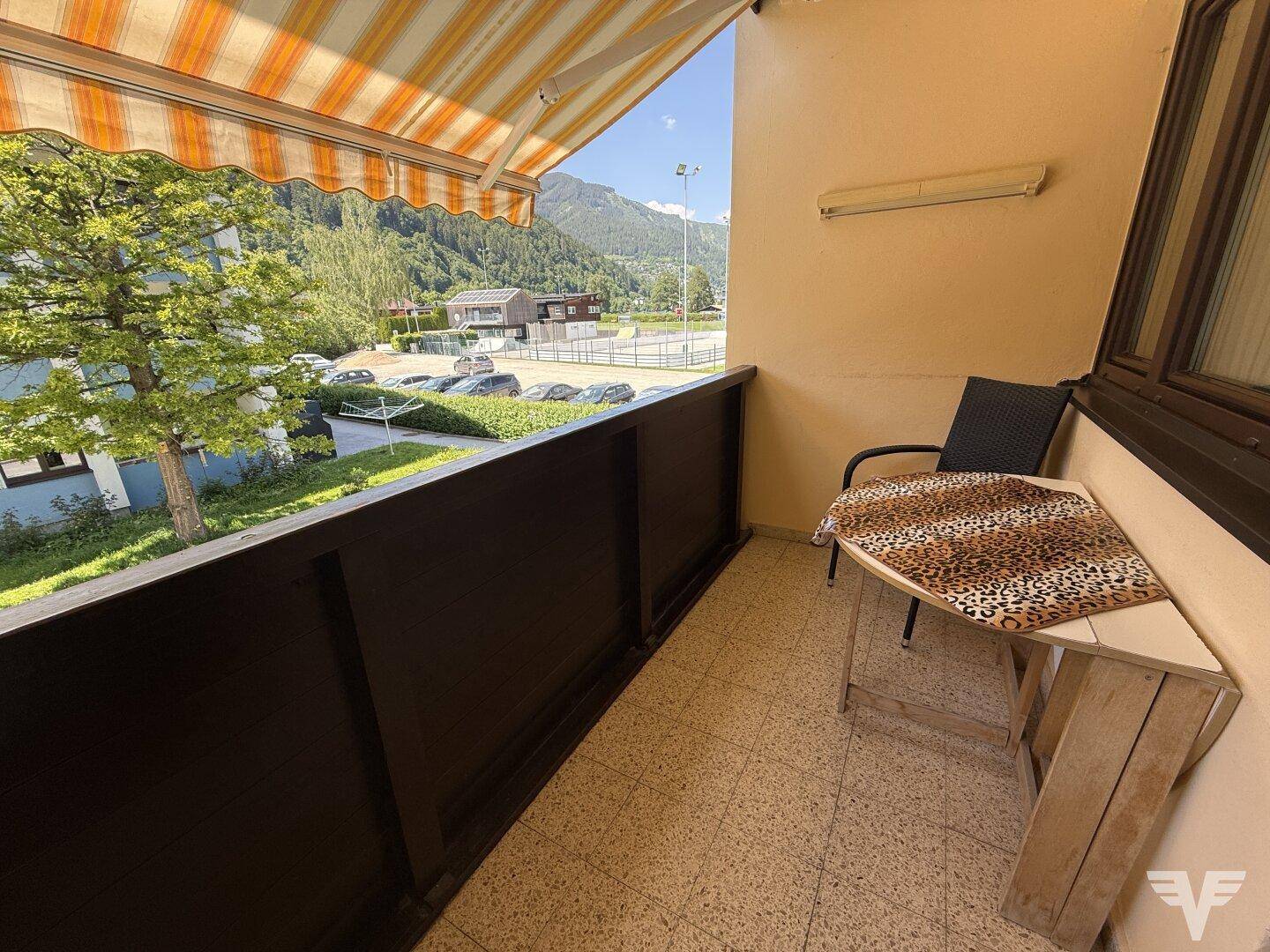 Gemütlicher Balkon mit Markise, kleinem Tisch und Bergblick.