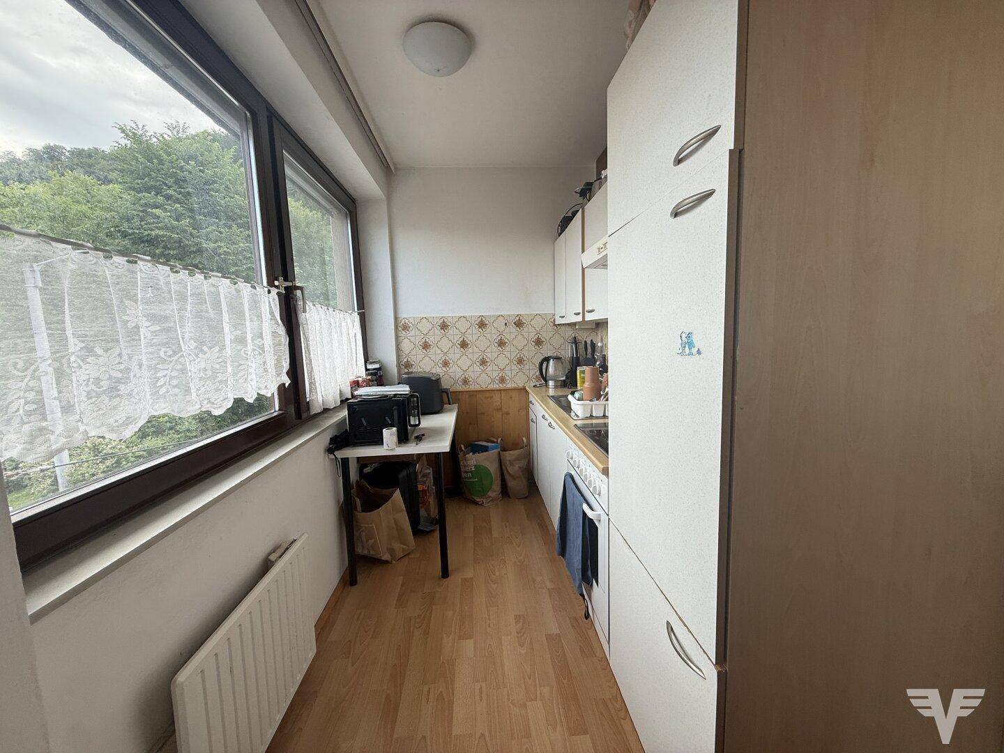 Kleine Küche mit Fenster, einfacher Ausstattung und Blick ins Grüne.