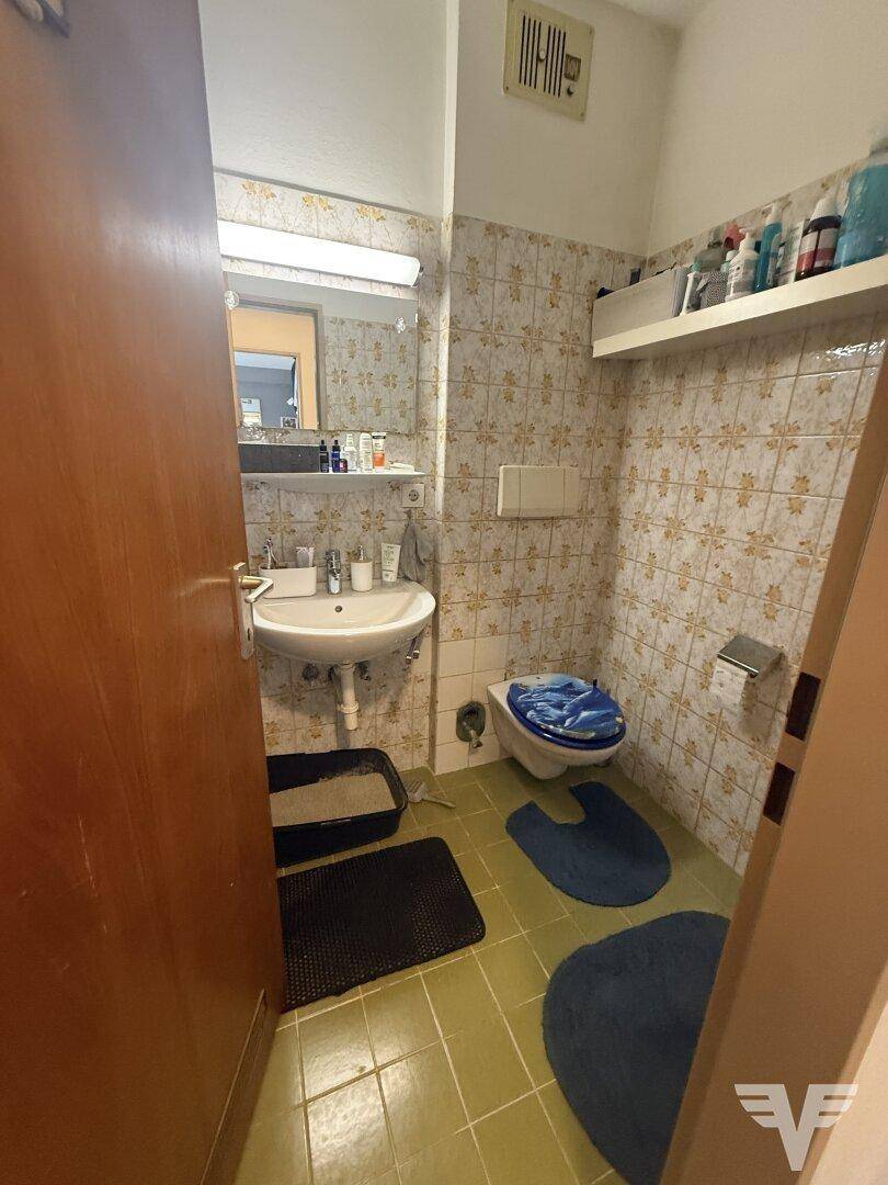 Badezimmer mit grünen Bodenfliesen, Wandfliesen und Waschbecken.