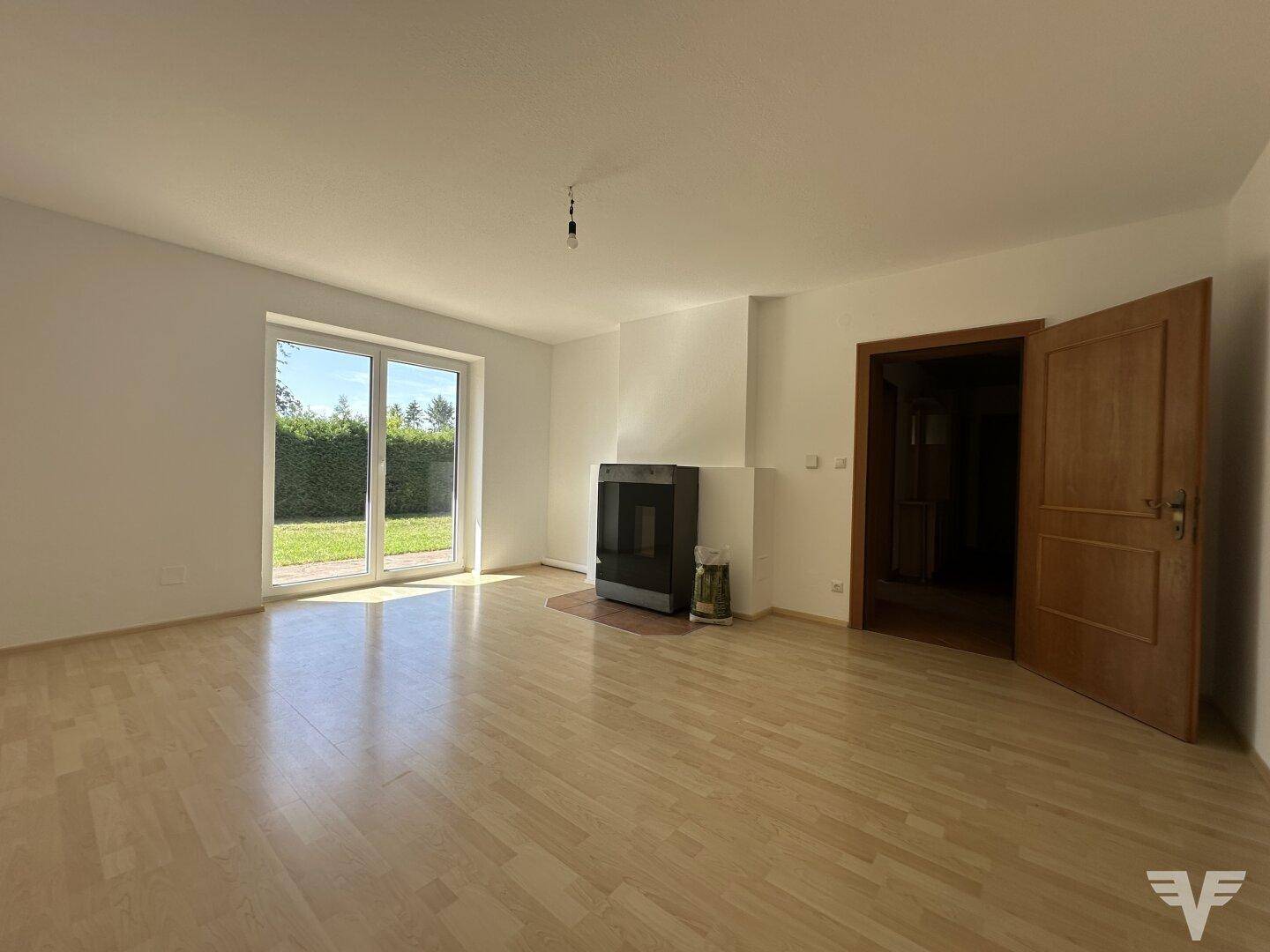 Helles Wohnzimmer mit Laminatboden, Kaminofen und direktem Zugang zum Garten.