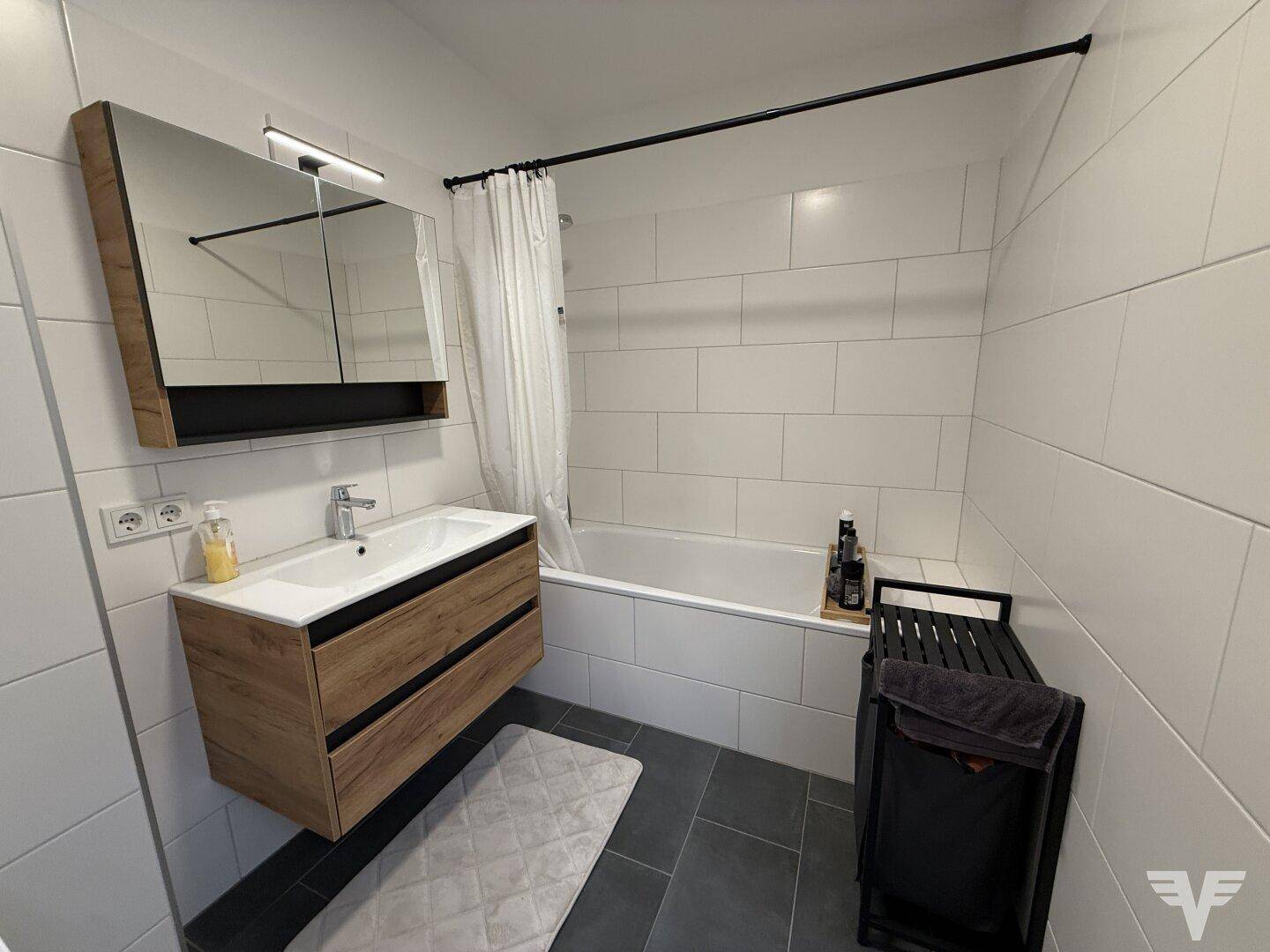 Modernes Badezimmer mit Badewanne, Waschtisch und weißen Wandfliesen.