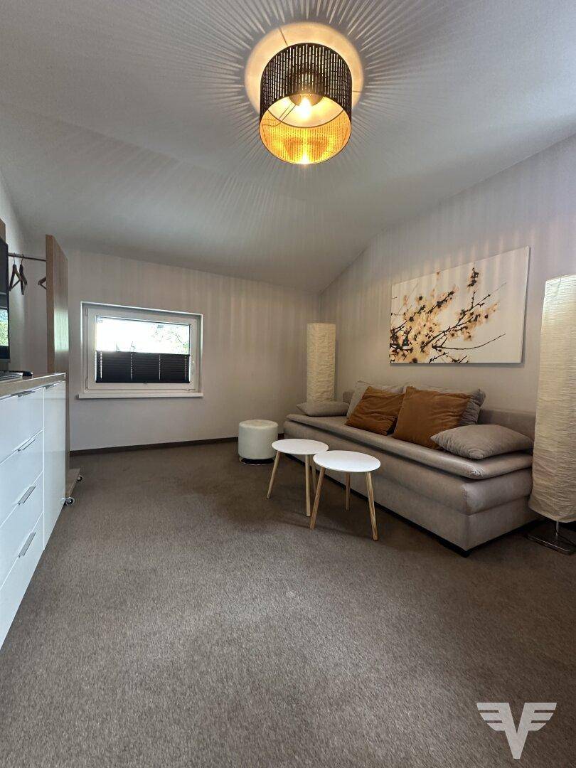 Gemütlicher Wohnbereich mit Sofa, Teppichboden und schräger Decke im Dachgeschoss.
