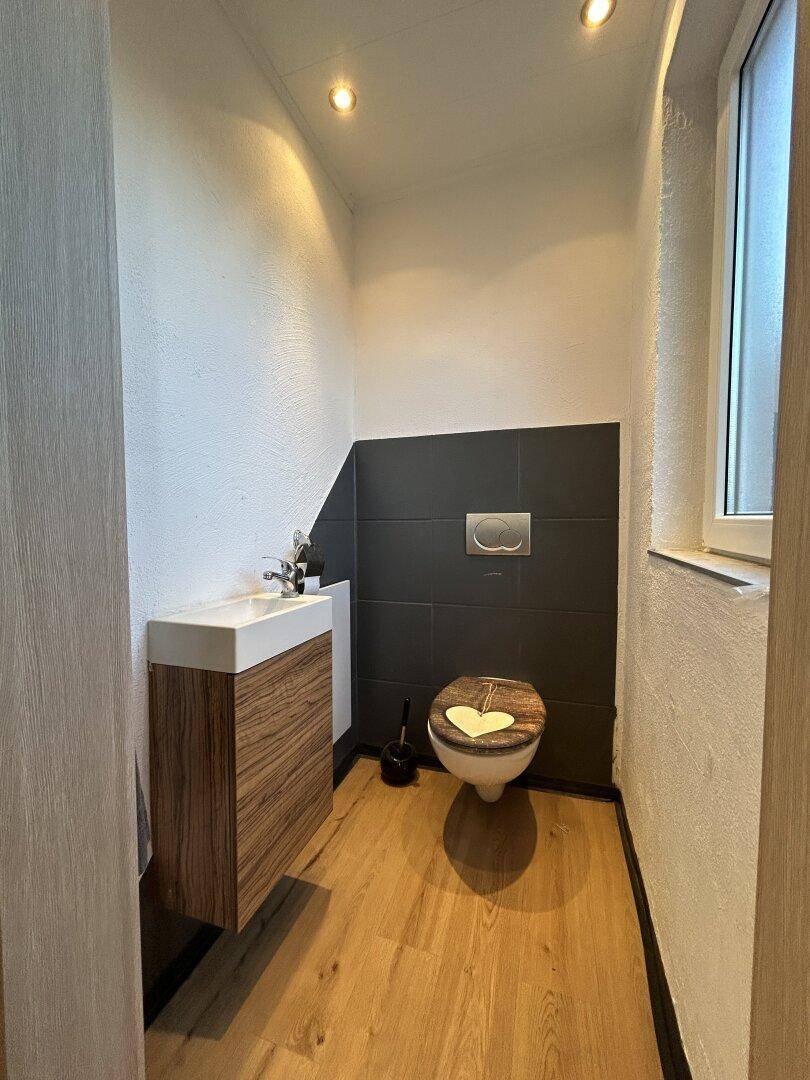 Modernes Gäste-WC mit schwebendem Waschtisch, wandhängendem WC und Fenster.