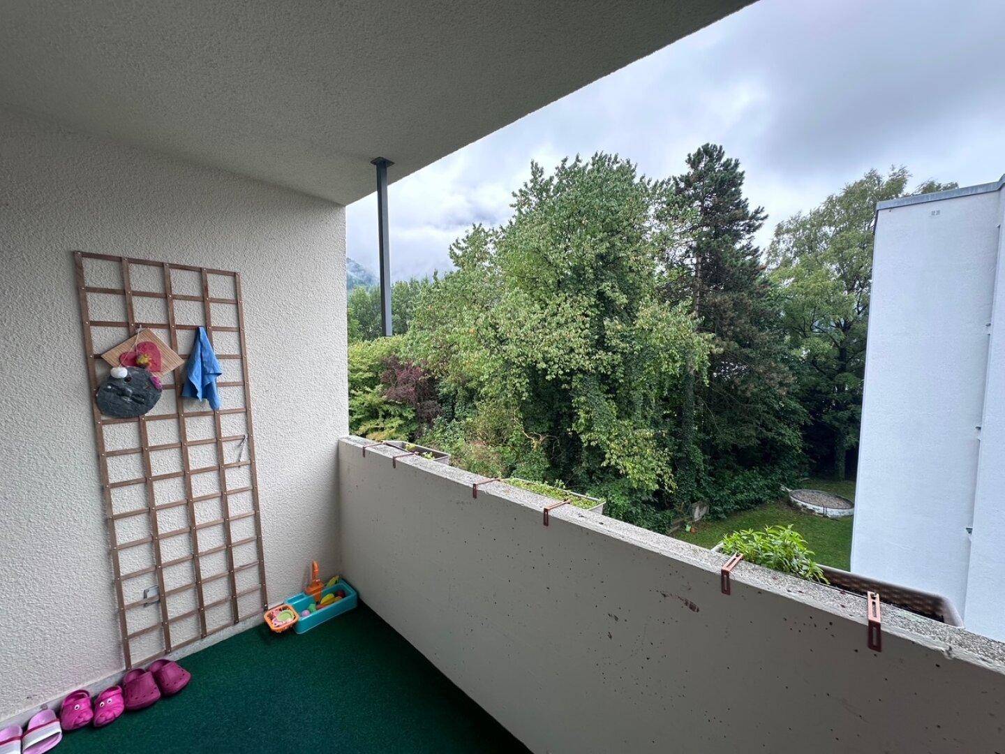 Balkon mit grüner Aussicht auf Bäume und entfernte Berge, ideal zum Entspannen.