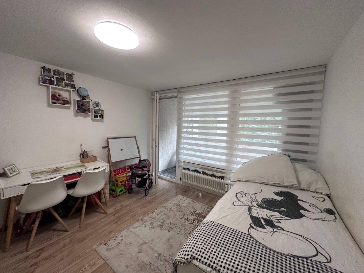 Kinderzimmer mit Einzelbett, Schreibtisch und direktem Zugang zu einem kleinen Balkon.