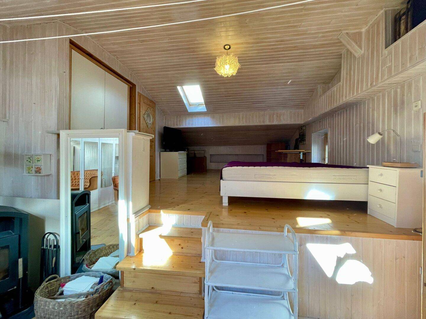 Offener Wohnbereich mit Schlafbereich auf einer erhöhten Plattform, Holzwänden und Dachfenstern.